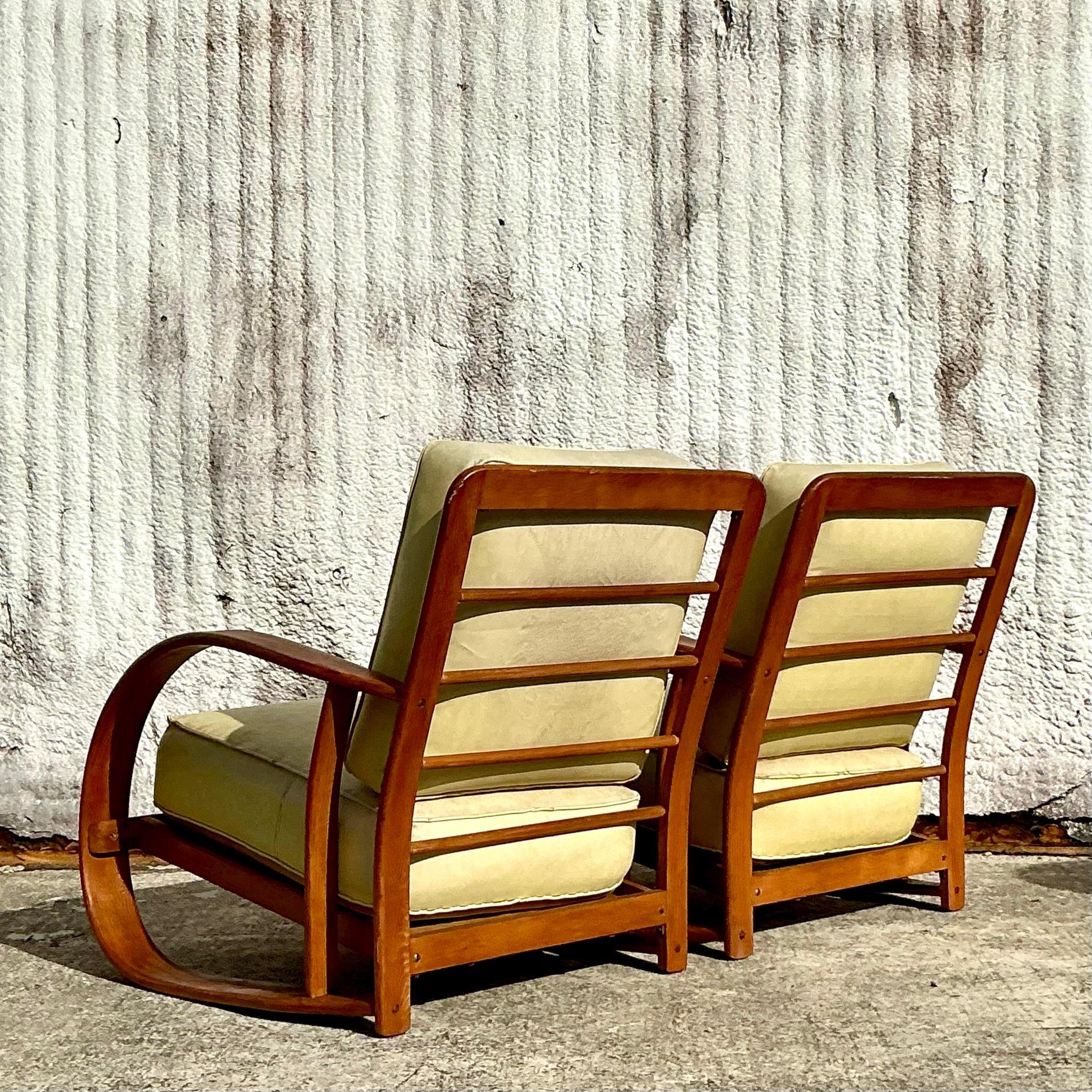 Introduce la sofisticación de la modernidad de mediados de siglo en tu espacio con este par de tumbonas de madera curvada vintage, inspiradas en los innovadores diseños de Gilbert Rohde. Estas sillas presentan elegantes armazones de madera curvada