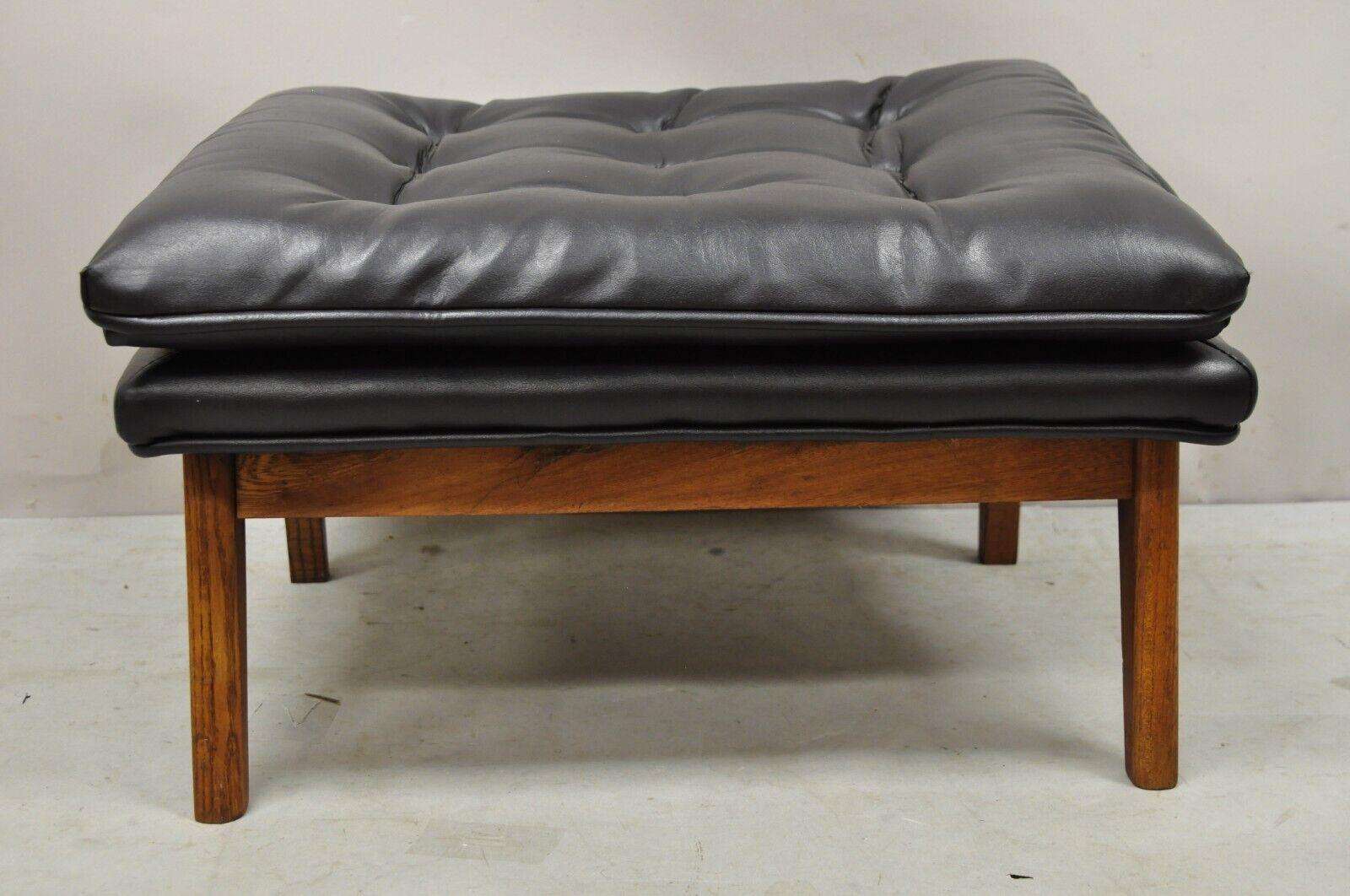 Vintage Mid-Century Modern black tufted vinyl lounge chair footstool ottoman. Item features black button tufted vinyl upholstery, solid wood frame, beautiful wood grain, tapered legs, clean modernist lines, quality American craftsmanship. Circa