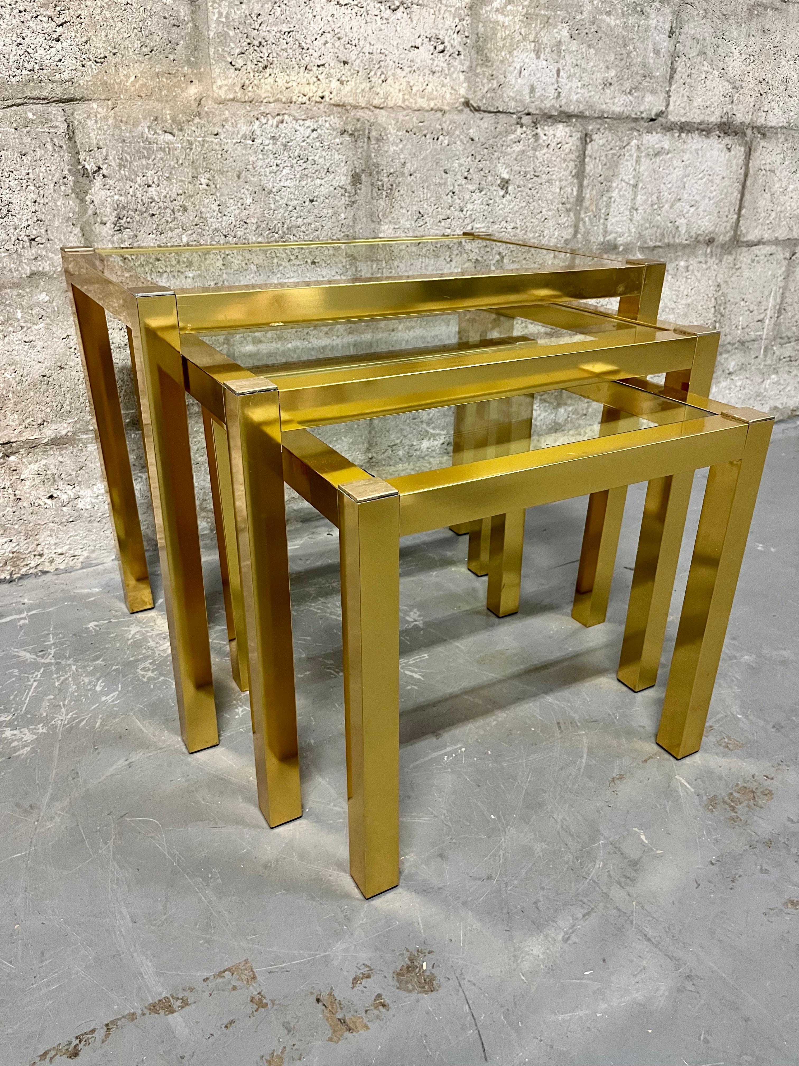 Set of Three Mid Century Brass Anodized Aluminum Nesting Tables. Circa 1960s 
Feature 1 Sq. Inch Brass Anodized aluminum tubing frames with removable glass tops. 
In very good original condition with minor signs of wear and age. There are some minor