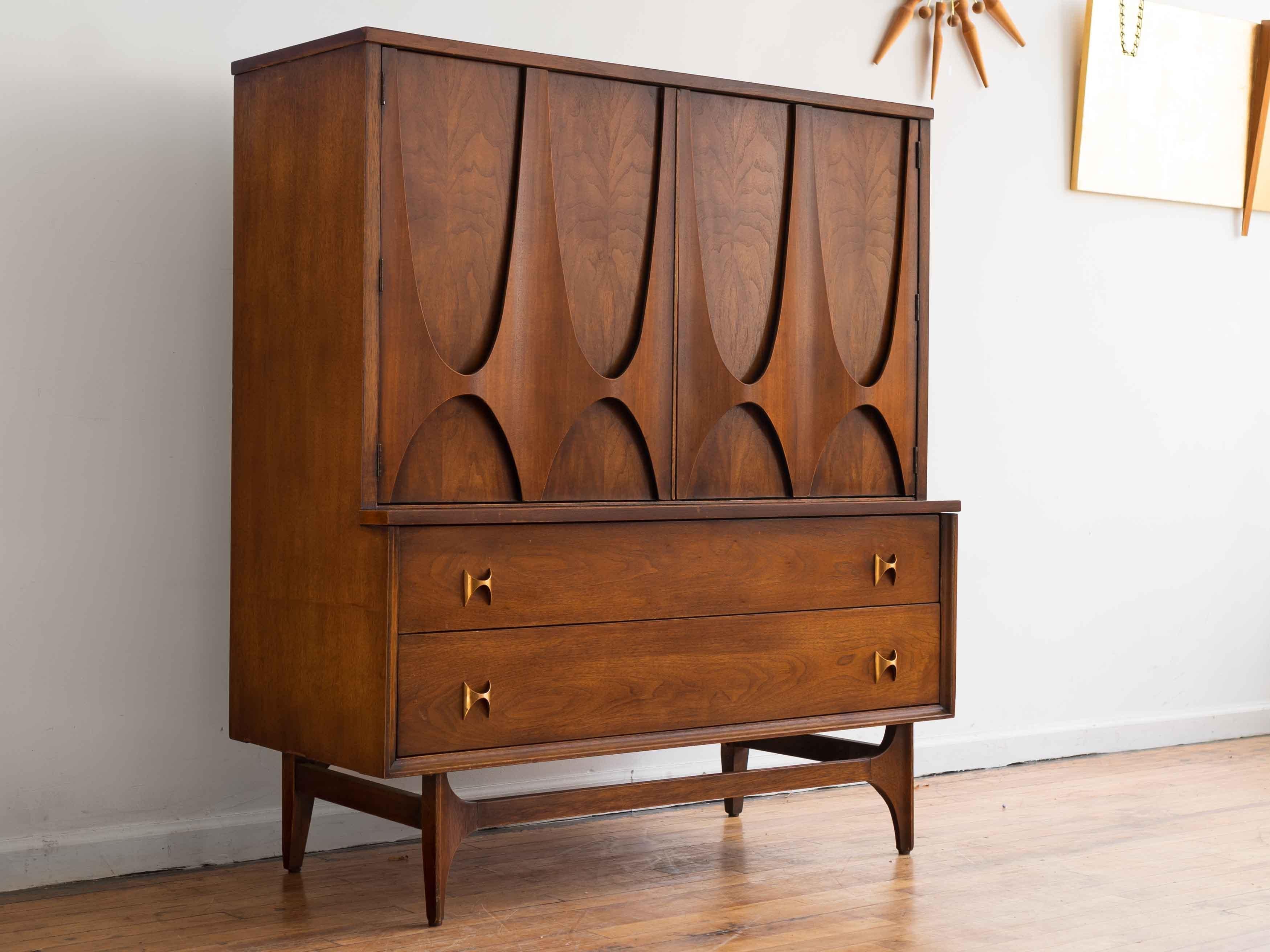 44” x 19” x 50”H

Iconic Broyhill Brasilia gentleman's chest in walnut. Two large doors with the line's signature motif conceal four small drawers and open shelving. Two full-size lower drawers. 

Very good vintage condition. Some minor finish nicks