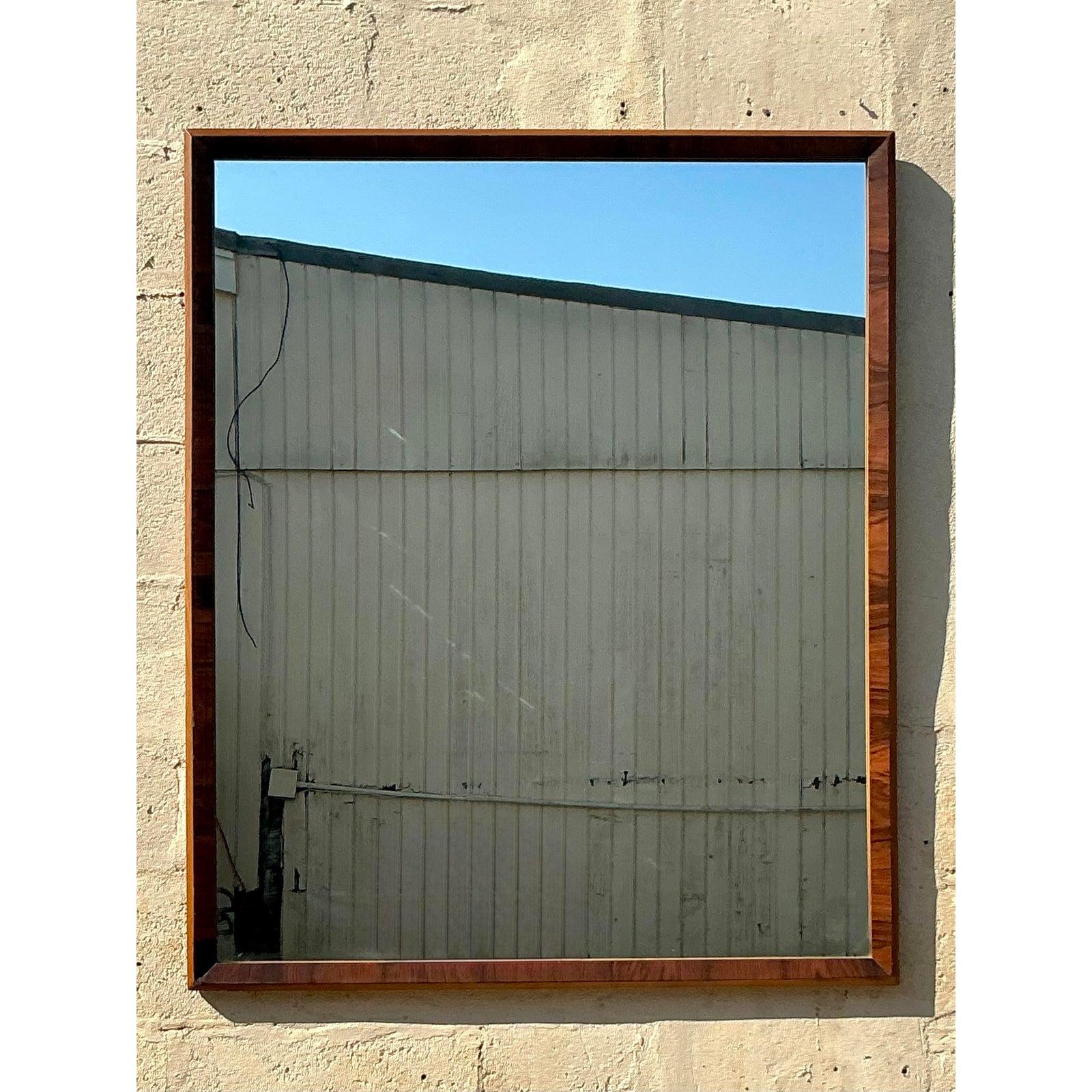 Añade un toque refinado a tu espacio con este impresionante espejo moderno de mediados de siglo de madera burl. El elegante armazón rectangular, fabricado en madera burl ricamente veteada, resalta la belleza natural del material con tonos cálidos y