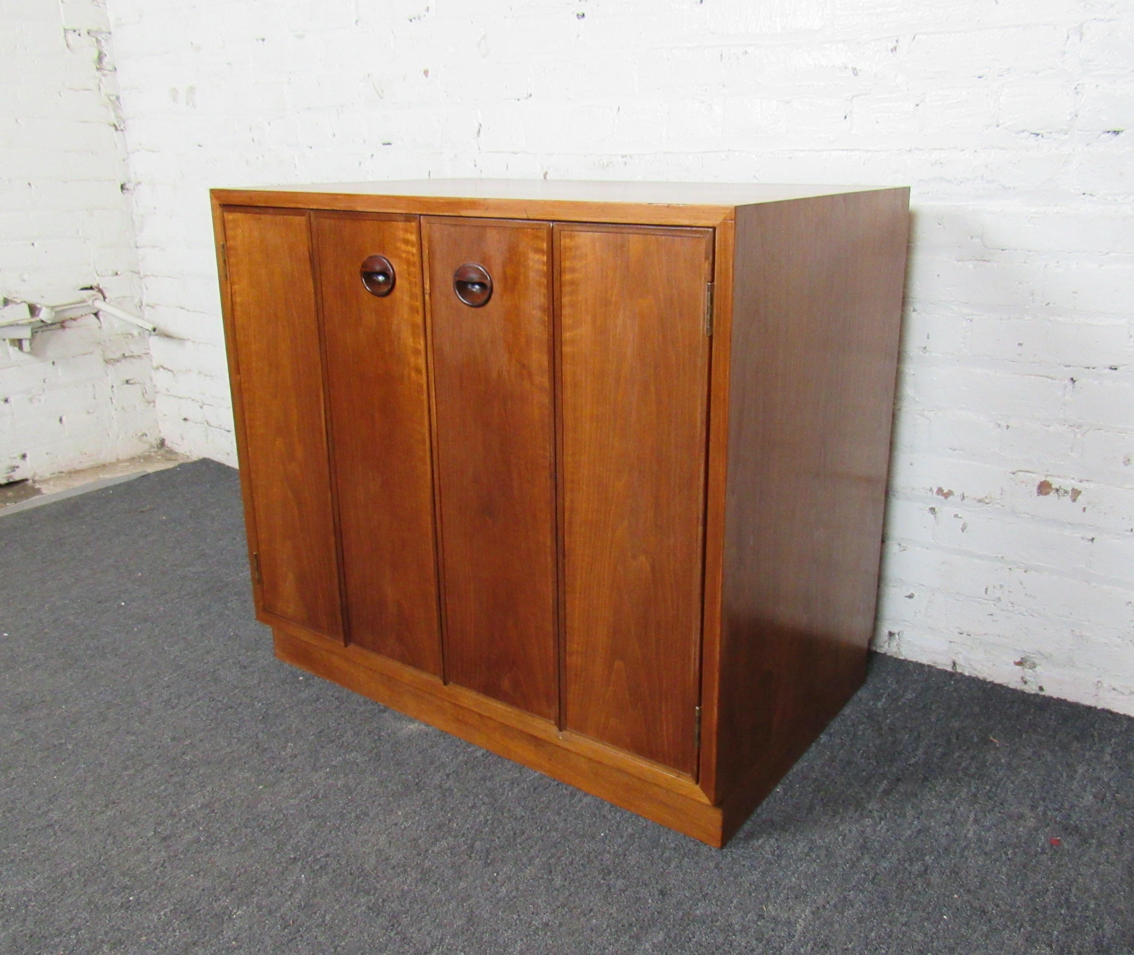 A compact and interesting Mid-Century Modern cabinet with sculpted wooden handles, this piece is a great and lasting addition to any home or office. Please confirm item location with seller (NY/NJ).