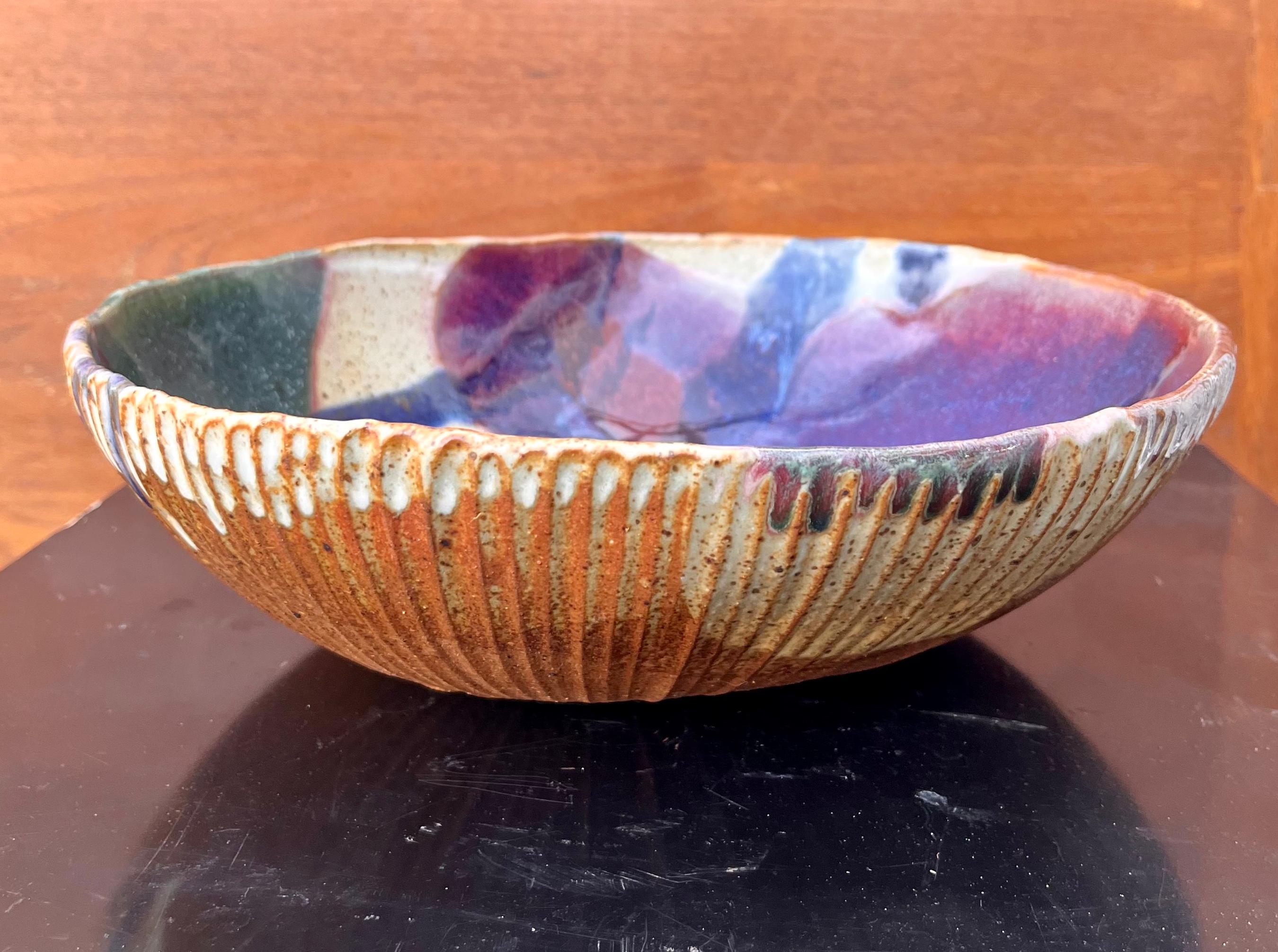 Vintage Mid Century Modern Ceramic Studio Signed Stamped Pottery Bowl. Circa 1960s 
Ce modèle d'inspiration brutaliste présente un extérieur partiellement émaillé et un intérieur à motifs abstraits en émail violet, vert chasseur, magenta et bleu