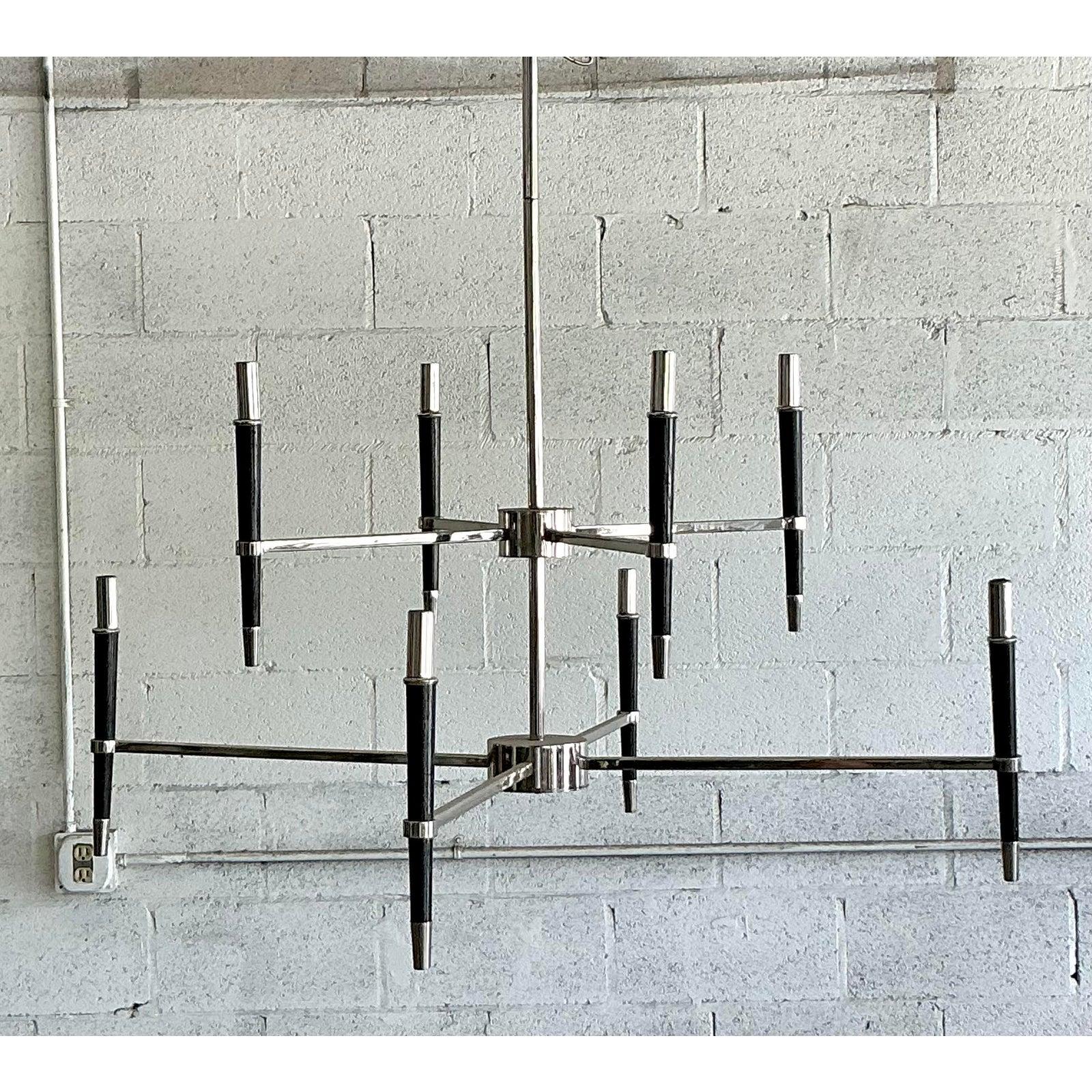 Este candelabro vintage de ocho brazos, un sorprendente ejemplo del diseño moderno de mediados de siglo, encarna las líneas limpias y arquitectónicas de la época. La pieza presenta un elegante marco cromado con brazos que irradian hacia fuera en una