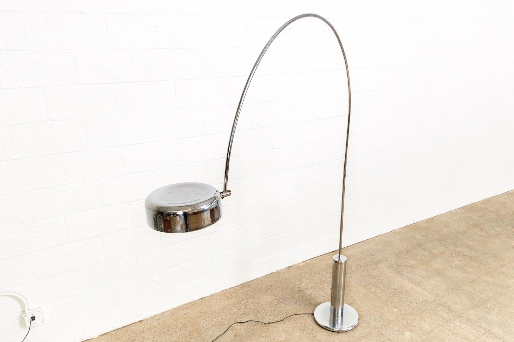This vintage mid century modern chrome arc floor lamp is circa 1960. The sleek modernist design features an elegant arching stem on a tall tubular chrome-plated steel base and a lozenge-shaped chrome lampshade with a milky white enameled interior.