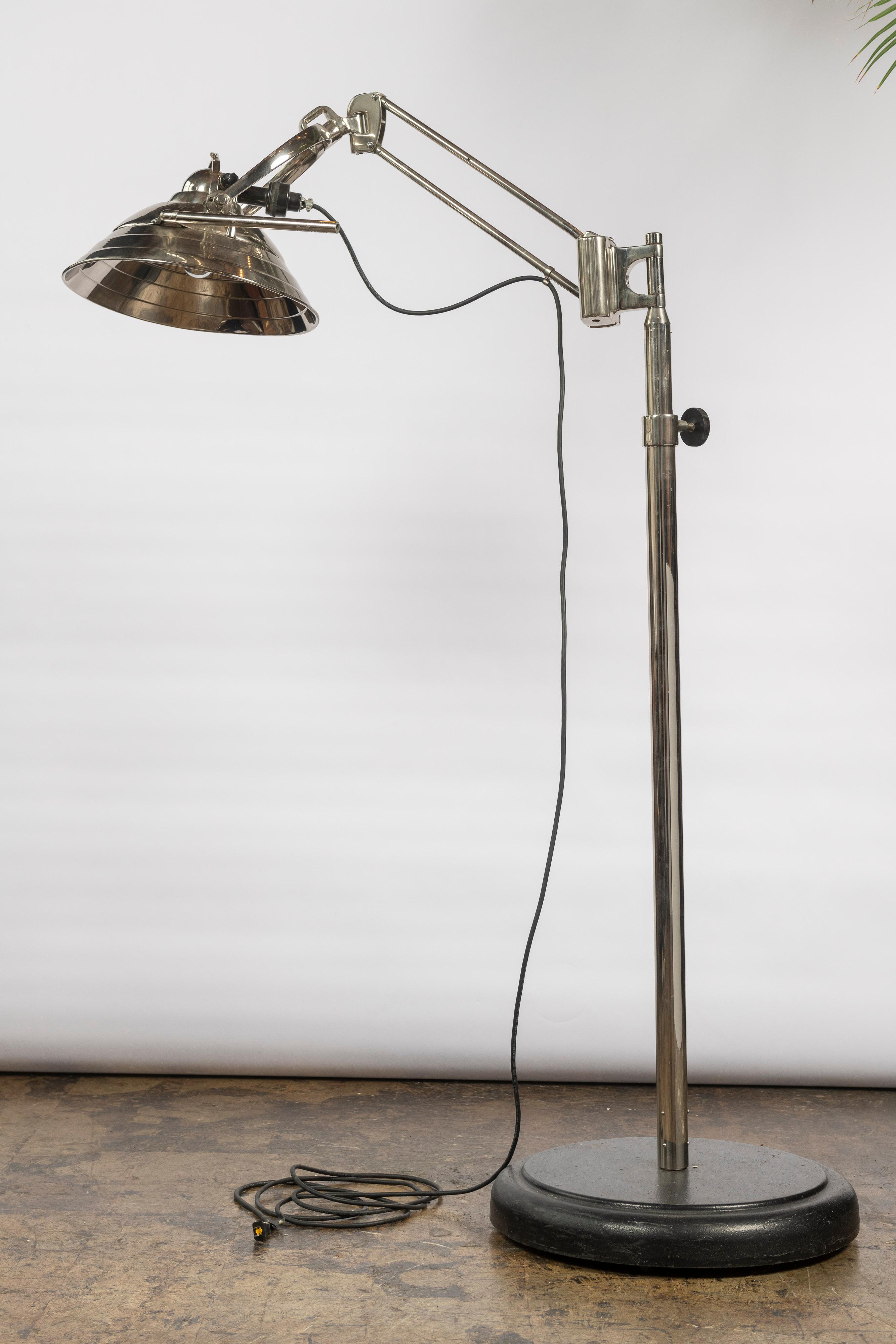 This large industrial style floor lamp is of Mid 20th Century origin and in very good condition. Made of chrome, the hooded shade is 17