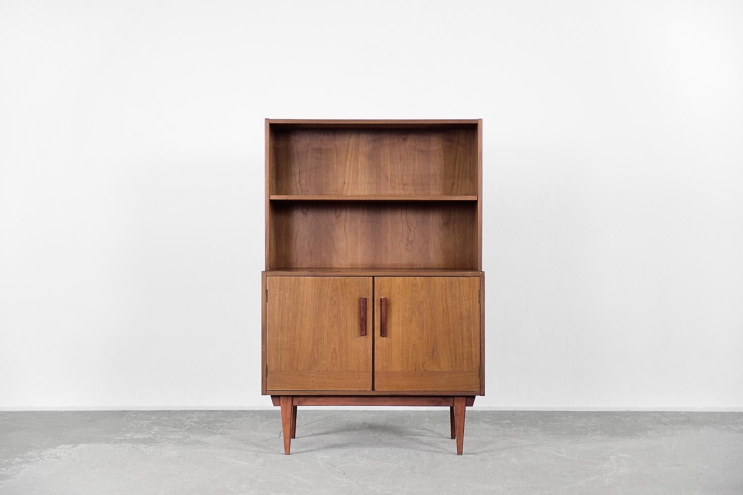 This classic cabinet was made in Sweden during the 1960s. It is finished with teak wood in a warm shade of brown. The cabinet has two shelves and the locker below. The oblong handles are made of teak. The piece of furniture is mounted on a wooden