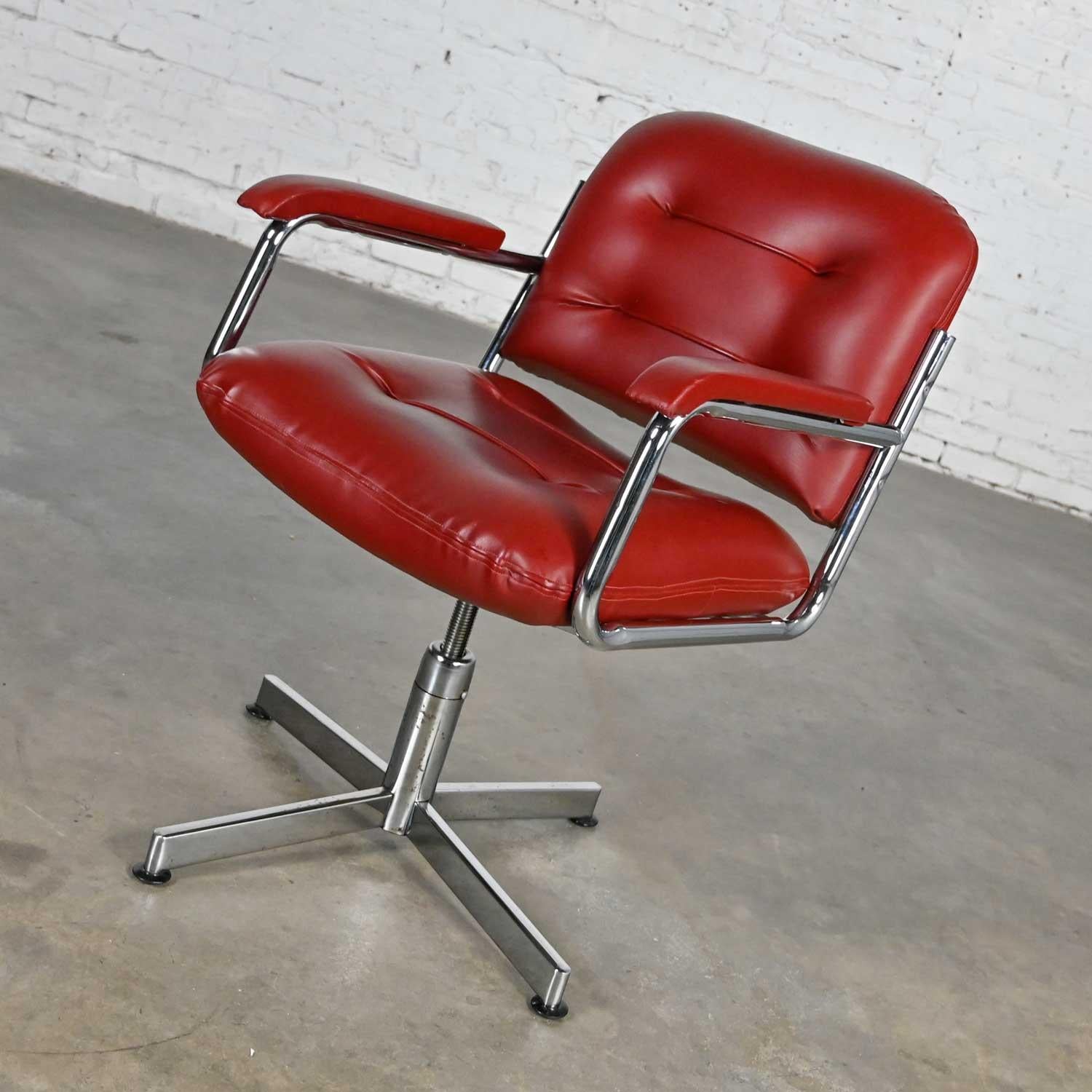 Wonderful vintage Mid-Century Modern cordovan color faux leather & chrome 4 prong base swivel and adjustable height desk chair by Manuchair Industries. Beautiful condition, keeping in mind that this is vintage and not new so will have signs of use