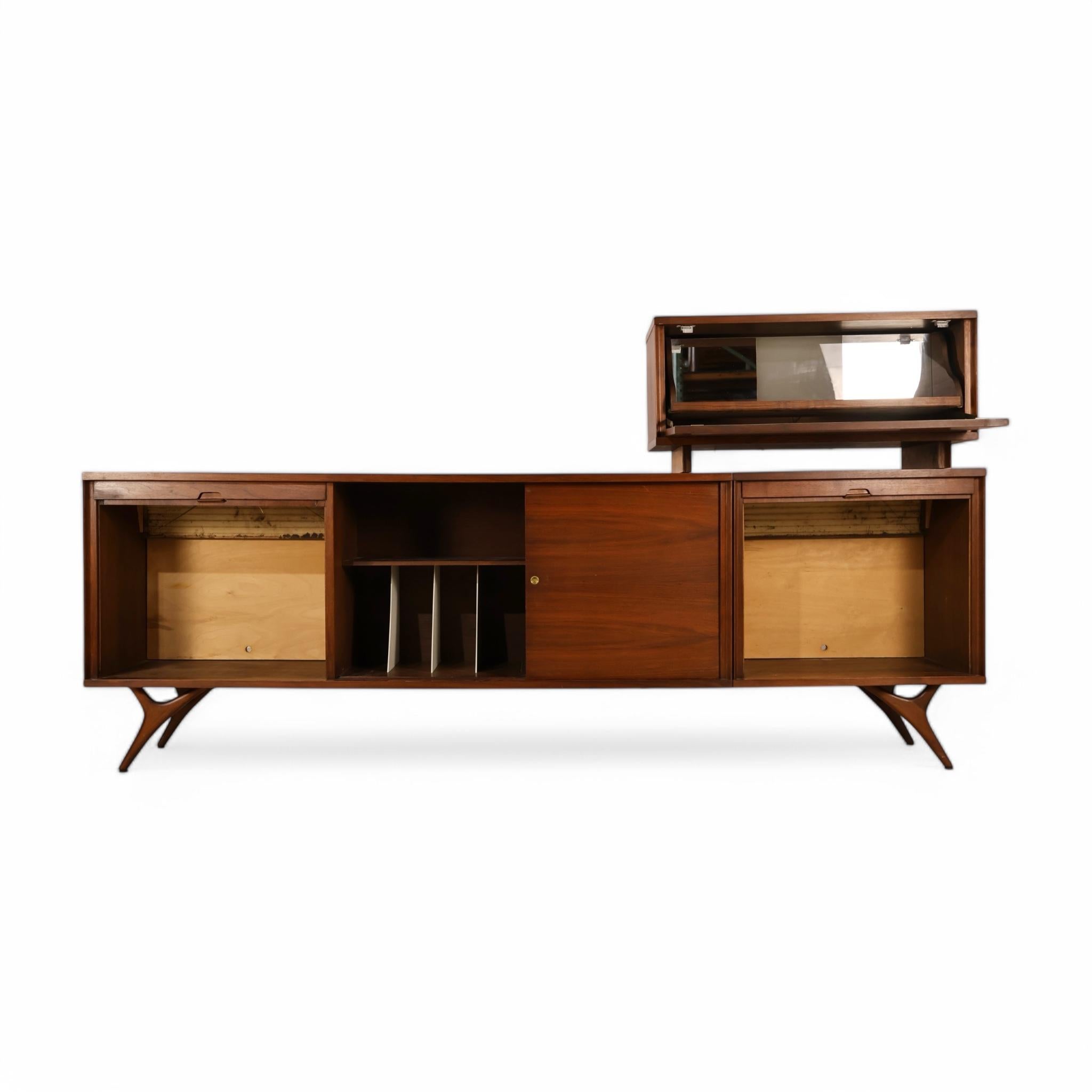 This stunning vintage 1960s walnut credenza is styled in the manner of Vladimir Kagan and showcases the bold, sculptural lines that define the era’s best design. Its sharply angled legs and sweeping profile give the piece a dynamic presence, while