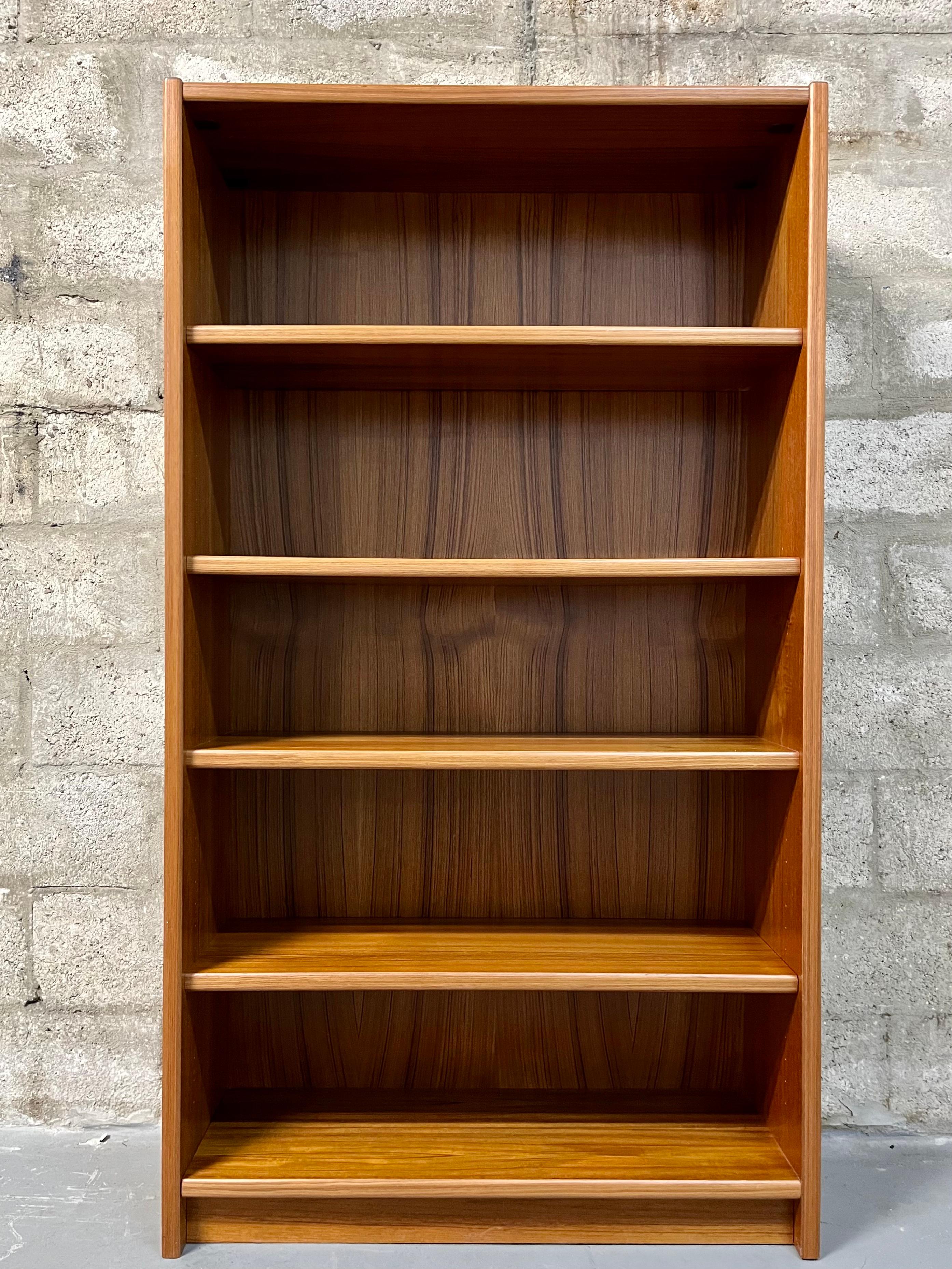 Vintage Mid Century Modern Danish Bookcase. C 1970s
Features a modern Scandinavian minimalist design with a beautiful teak wood grain. Offers plenty of storage space with three adjustable floating shelves edged with solid teak profiles. The