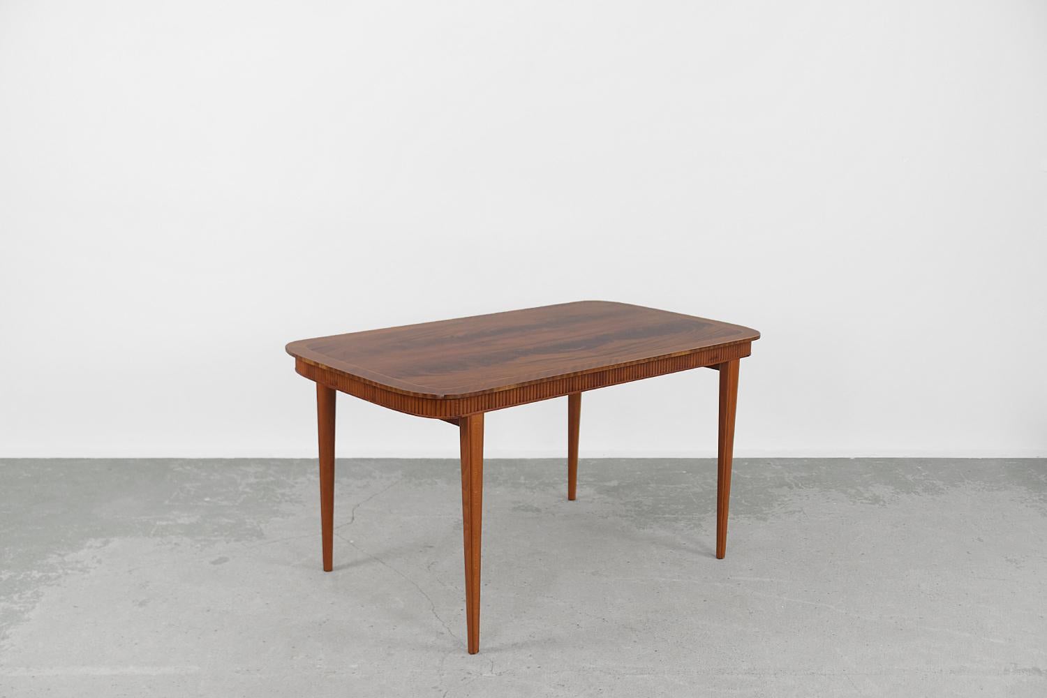 This classic table was made in Denmark during the 1960s. It has been finished of solid wood. The top has a strong and beautiful graining. The piece of furniture is distinguished by a decorative edge under the top. Turned legs are tapered and