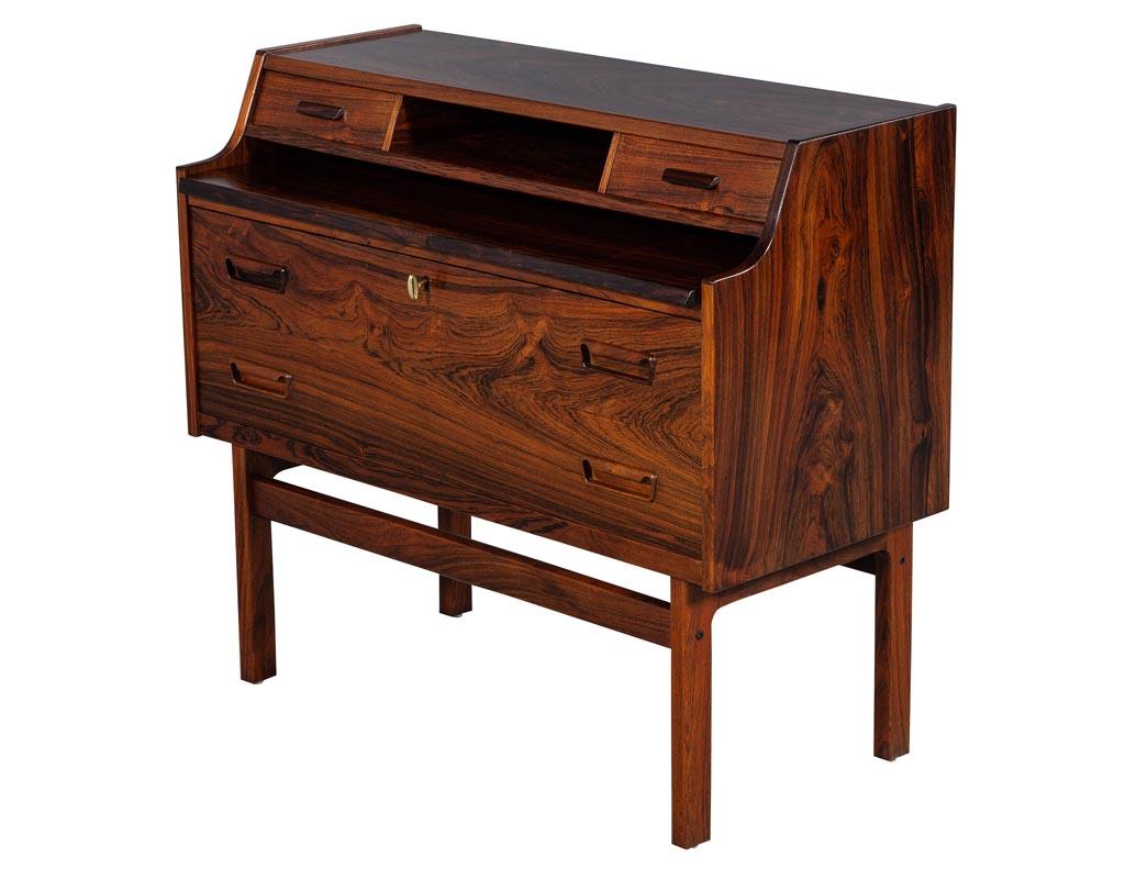Vintage Mid-Century Modern writing desk, made in Denmark. This desk has a pullout writing surface and two large drawers with a lock and the convenience of drawers and a top cubby. This desk is compact and perfect for a home office.