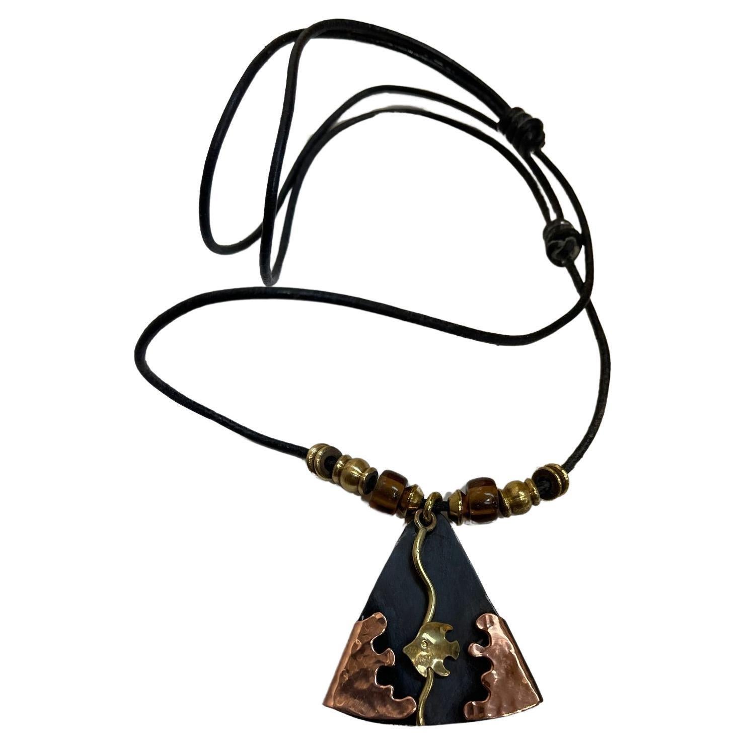 Simply Beautiful! Vintage Designer Signed Abstract Mid Century Modern Pendant Necklace. Featuring Hand crafted Golden Fish and Copper Waves on Triangular Black Lucite. Suspended from a Black Leather cord, measuring approx. 21.5