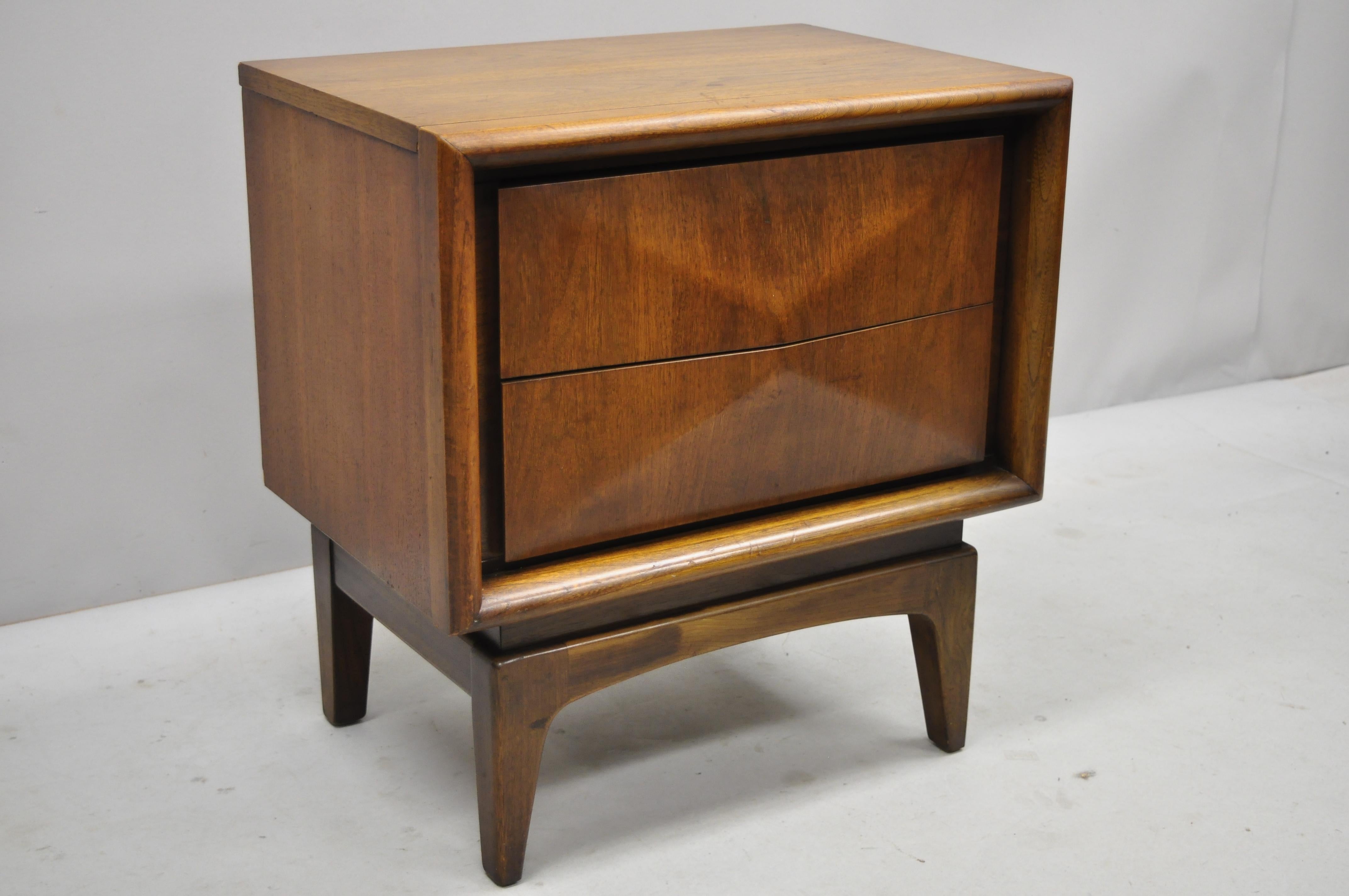 Vintage Mid-Century Modern diamond front walnut nightstand by United Furniture. Item includes 3 dimensional diamond front, beautiful wood grain, 2 dovetailed drawers, tapered legs, clean modernist lines, sleek sculptural form. Mid-20th century.