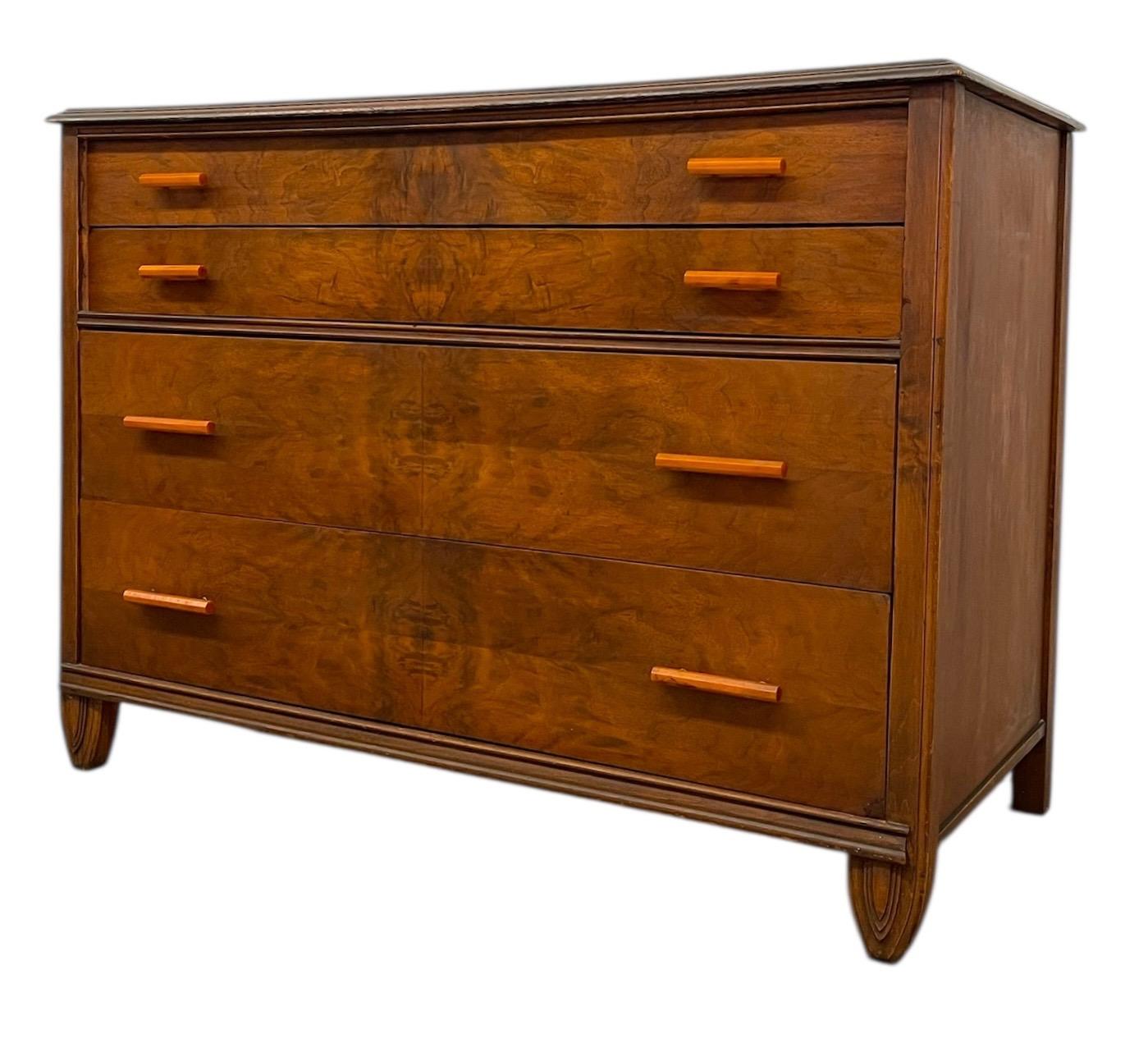 This vintage Art Deco dresser features clean lines, warm wood grain, and practical storage with four spacious drawers. The front showcases book-matched veneer patterns, giving the piece a sense of symmetry and visual depth.Each drawer is fitted with