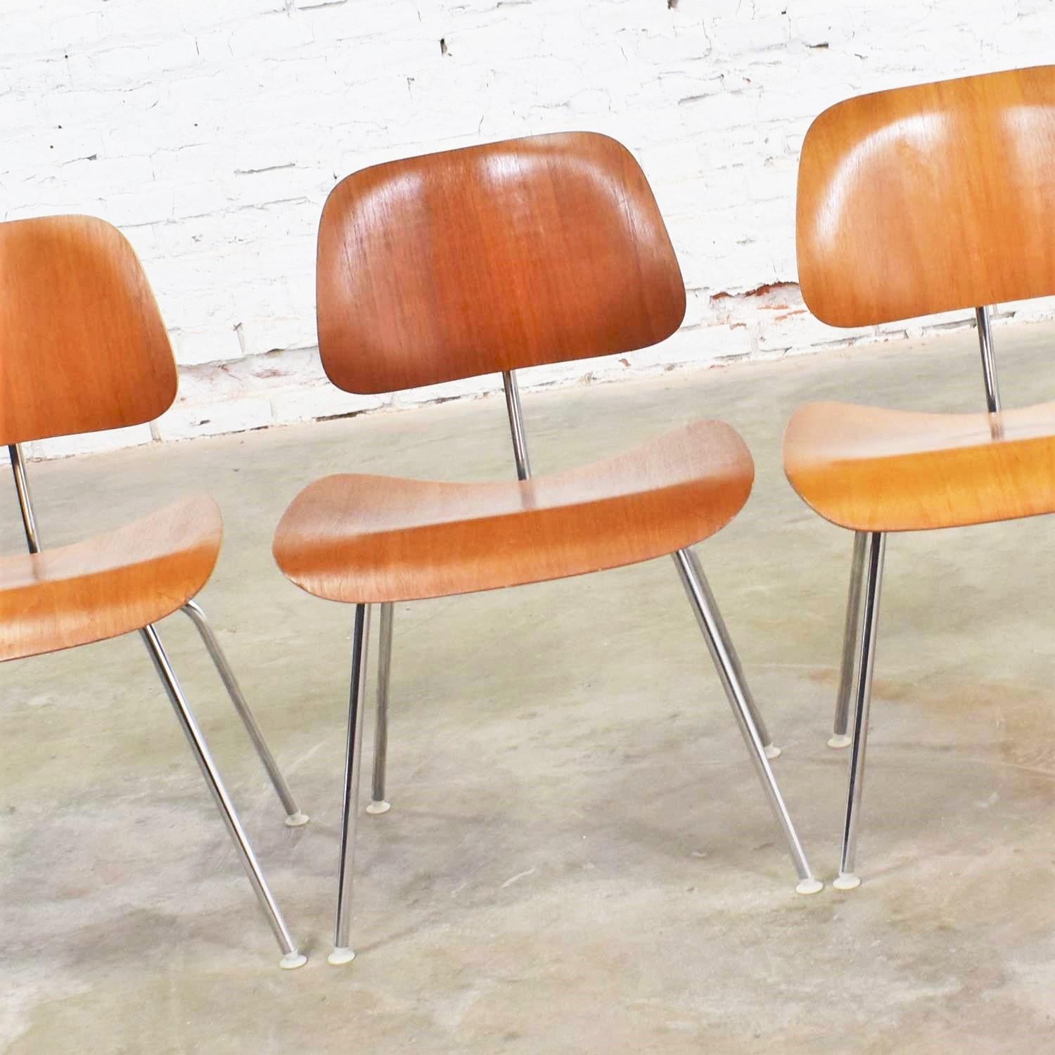 Handsome set of 4 vintage Mid-Century Modern Eames DCM, dining chair metal, dining chairs for Herman Miller with silver colored bases, white nylon feet, and walnut veneer. They are in overall wonderful vintage condition. There are some small flaws