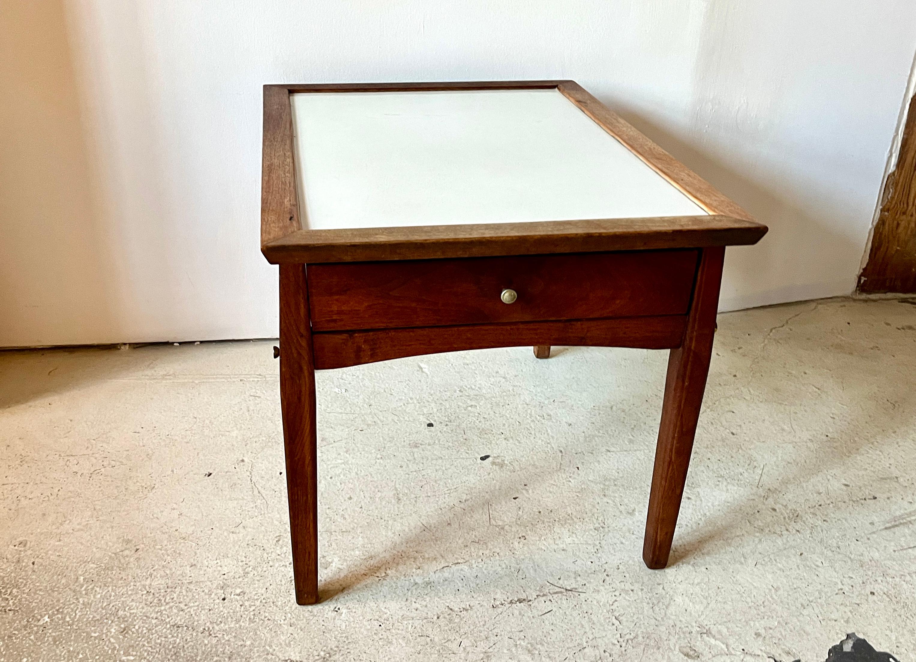 Vintage MCM Beistelltisch wahrscheinlich von Mersman oder ähnlichem (nicht markiert). Massivholz mit weißer Resopalplatte und dekorativen Messingverzierungen an den Seitenfugen.

Guter unrestaurierter Vintage-Zustand. Verfärbungen an einer Stelle