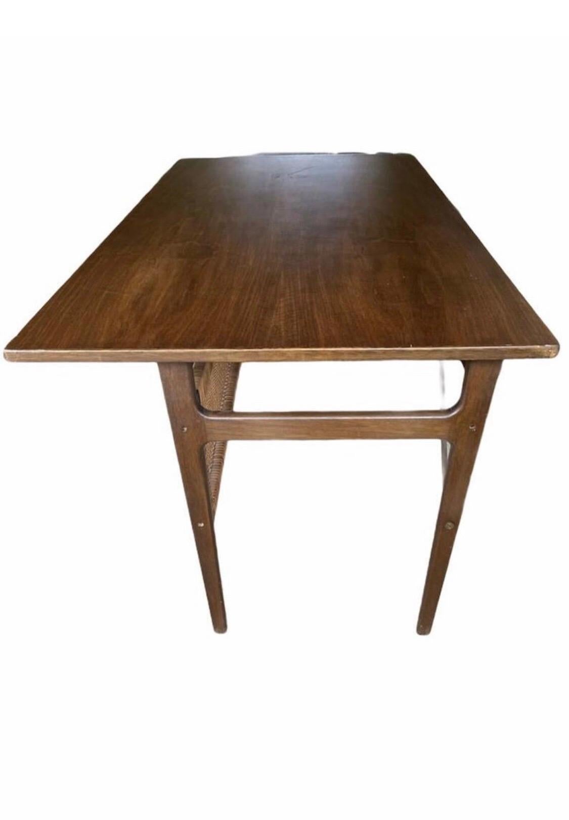 This beautiful Mid-Century Modern desk features sculpted metal pulls, a finished back, and a vintage walnut finish. A stylish design with a large top and plenty of room for storage within its five large drawers. This unique desk makes the perfect