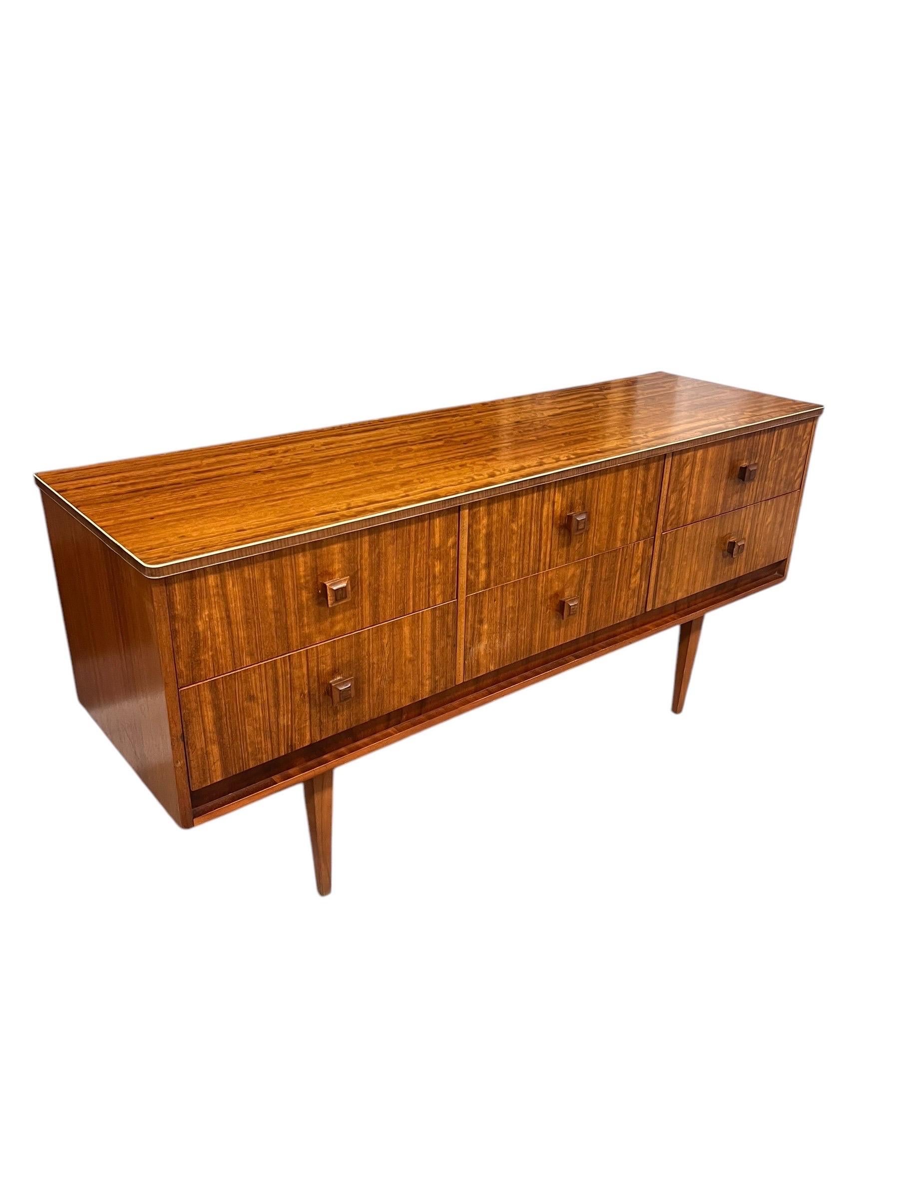 Diese Vintage Mid Century Modern TV Media Console oder Credenza ist ein auffallendes Stück, das die Eleganz und Funktionalität des Designs aus der Mitte des 20. Jahrhunderts verkörpert. Er ist aus wunderschön gemasertem Holz gefertigt und weist ein