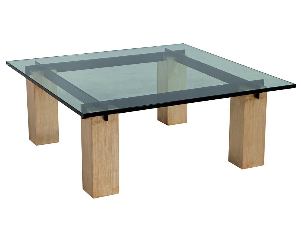 Vintage Mid-Century Modern glass top coffee table. Featuring sleek black metal beams supported by brass and silver leaf columns. Original glass has minor scratches consistent with age and use. Price includes complimentary curb side delivery to the