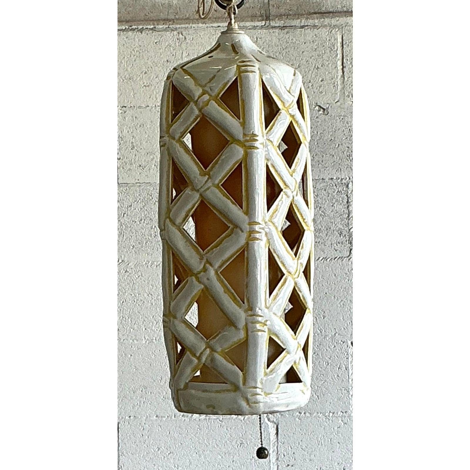 Diese exquisite Hängelaterne im Vintage-Stil verleiht Ihrem Raum den zeitlosen Charme des Hollywood-Regency-Stils. Dieses Stück besteht aus einem wunderschön gefertigten glasierten Keramikkörper, der in ein kompliziertes Bambusspalier gemeißelt ist,