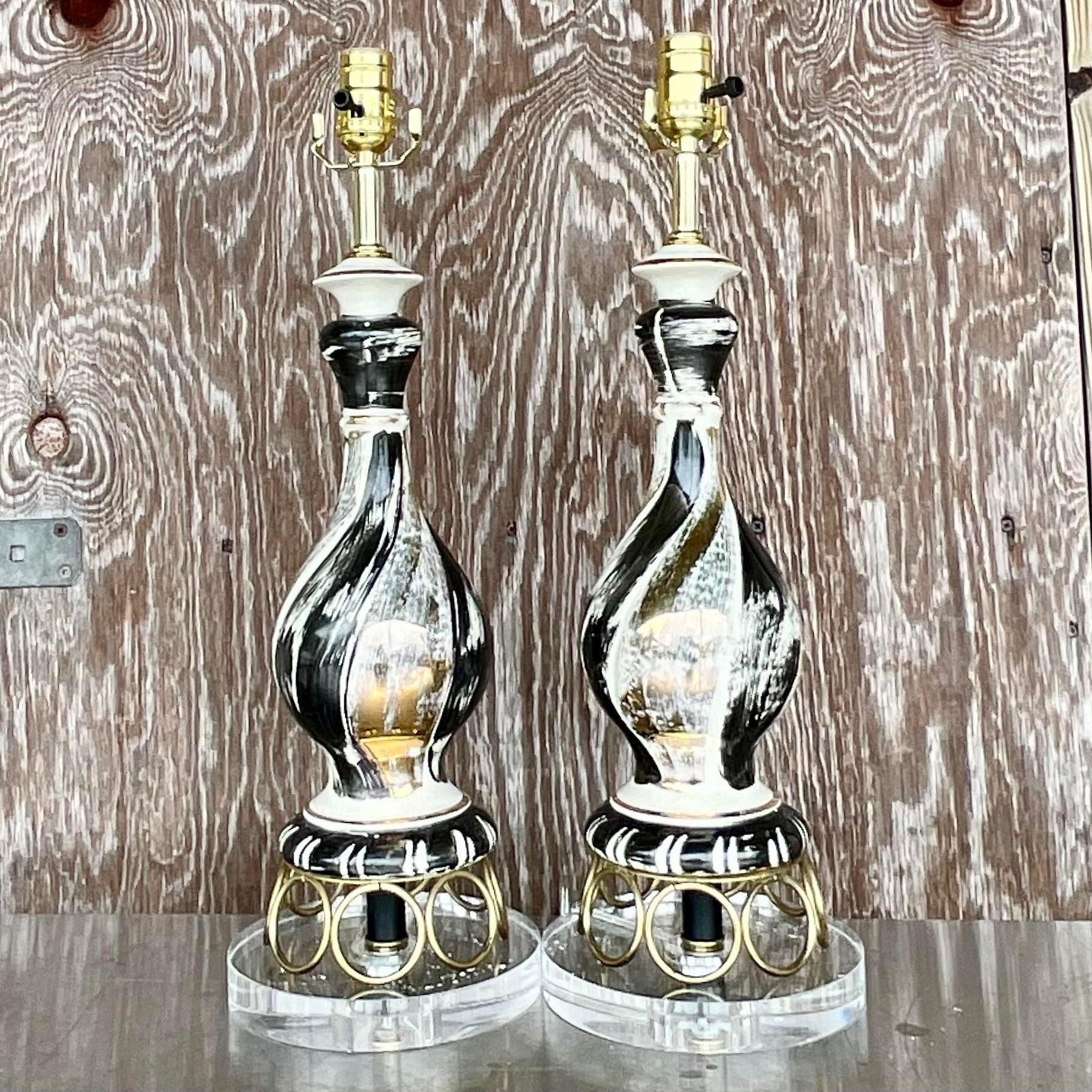 A fantastic pair of vintage MCM table lamps. Beautiful black and gold strokes on a white glazed ceramic background. Chic gold rings rest on a new lucite plinth. Fully restored with all new wiring and hardware. Acquired from a Palm Beach estate.