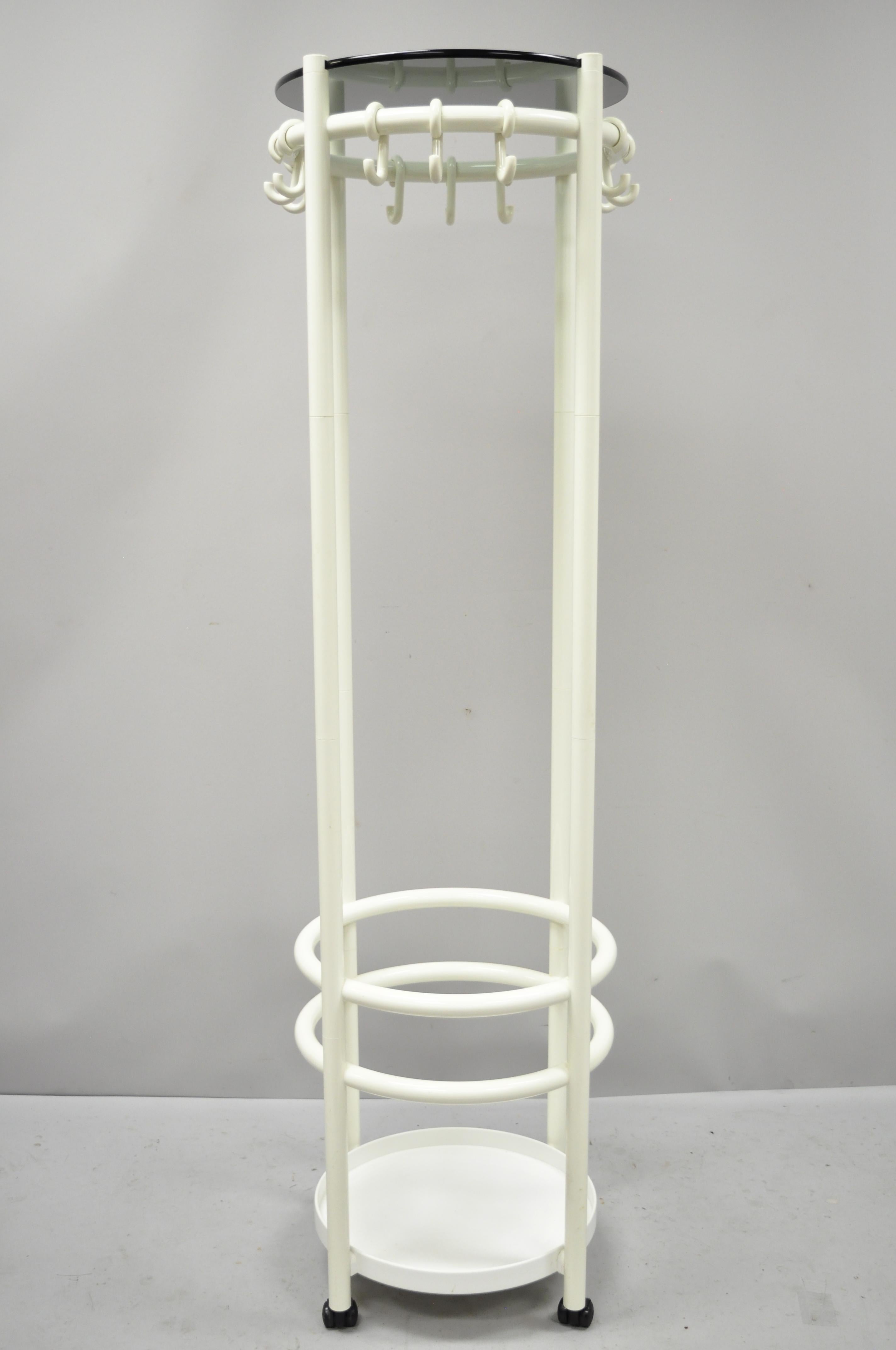 Vintage Mid-Century Modern Space Age Joe Colombo style coat tree umbrella stand. Item features white coated plastic frame, 12 hooks, lower umbrella / cane stand holder, round smoked glass top, rolling casters, very nice vintage item, clean modernist