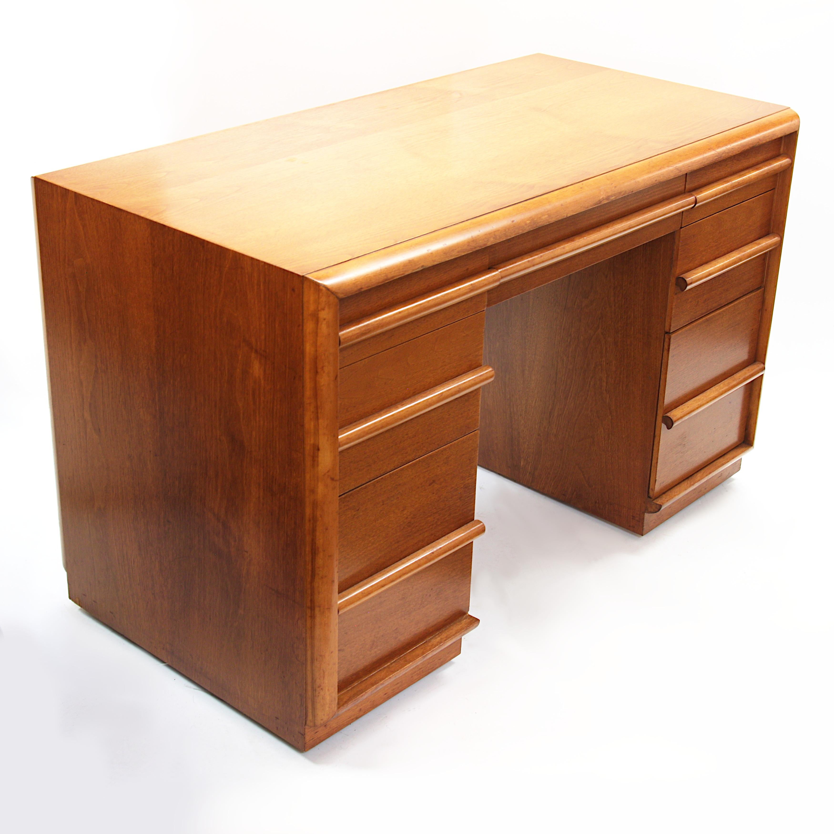 Wonderful little writing desk by the acclaimed T.H. Robsjohn-Gibbing for the Widdicomb Furniiture Co. Desk features a walnut cabinet with linear trim and pulls and recessed casters for easy positioning/moving. A beautiful original example from a