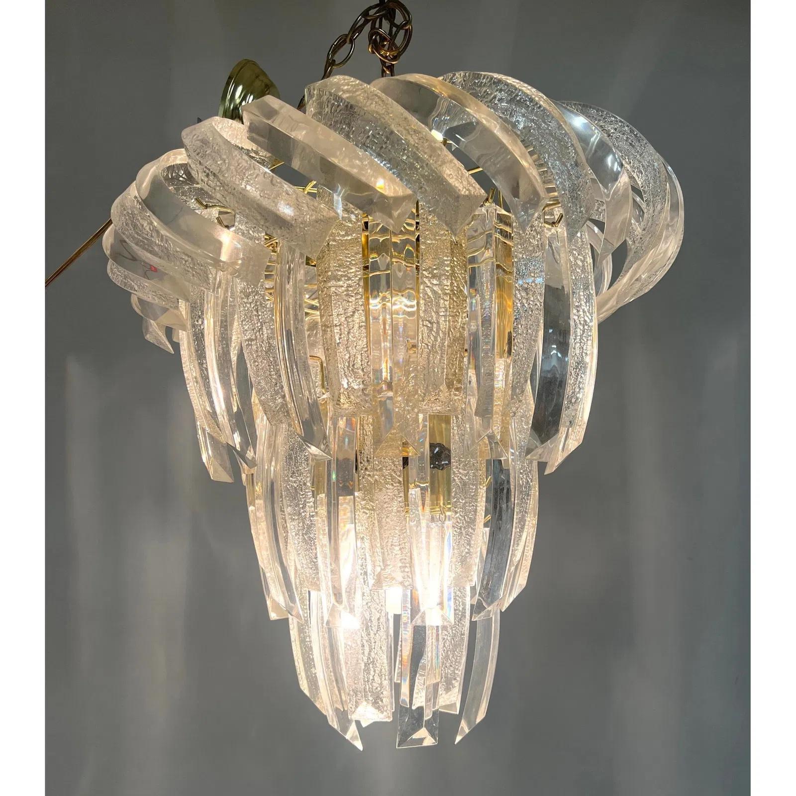 The Lucite chandelier showcases a stunning clear swirl design, embodying the sleek and innovative aesthetic of Mid-Century Modern lighting. Crafted in the 1970s, the chandelier highlights the era's fascination with Lucite, a lightweight and durable