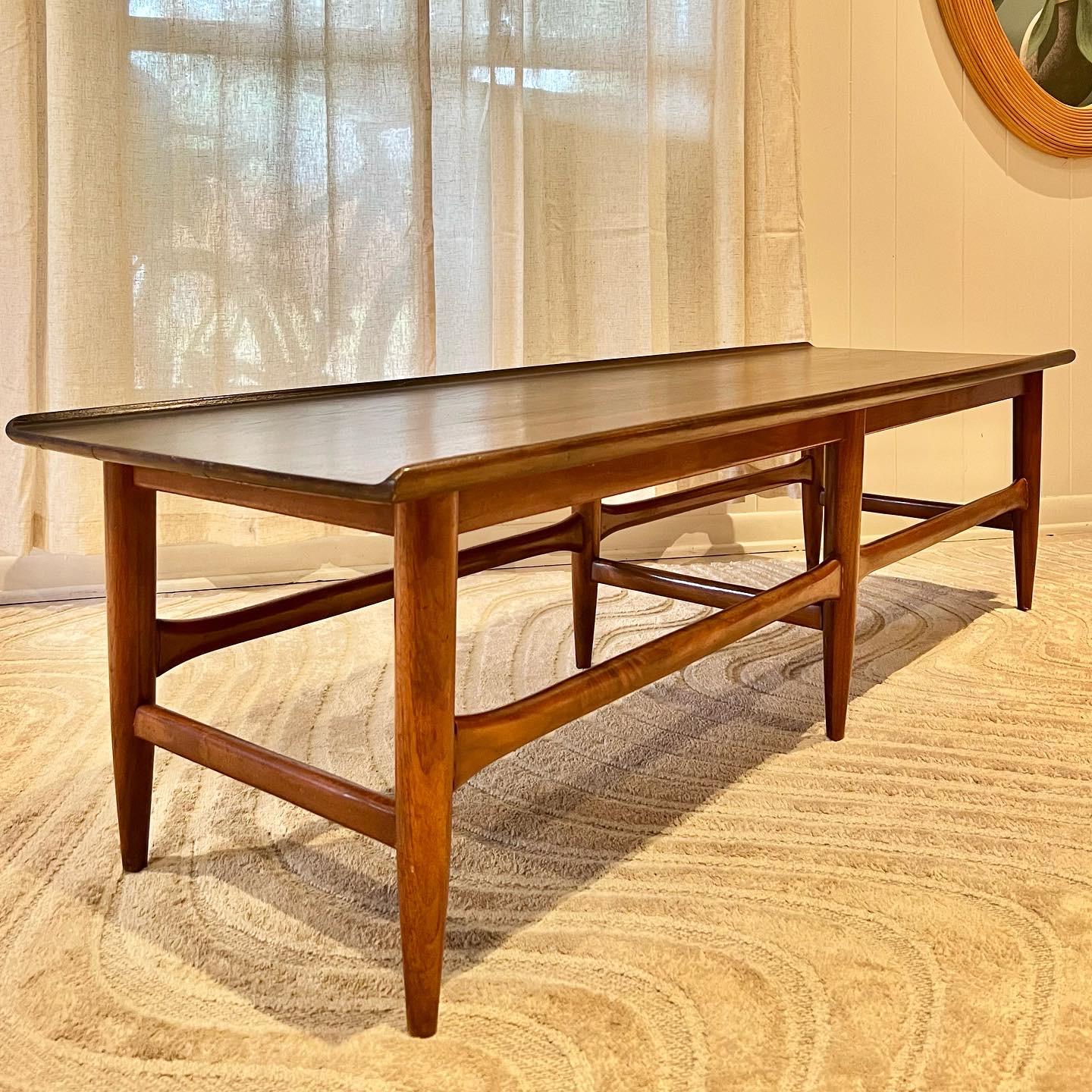 Vintage Mid-Century Modern coffee table with lots of curves and tapered legs. This beauty is 60 inches wide and has lots of space for all of your books and things! Overall in very good original condition. 

Dimensions:
16” H x 18” D x 60” W.
  