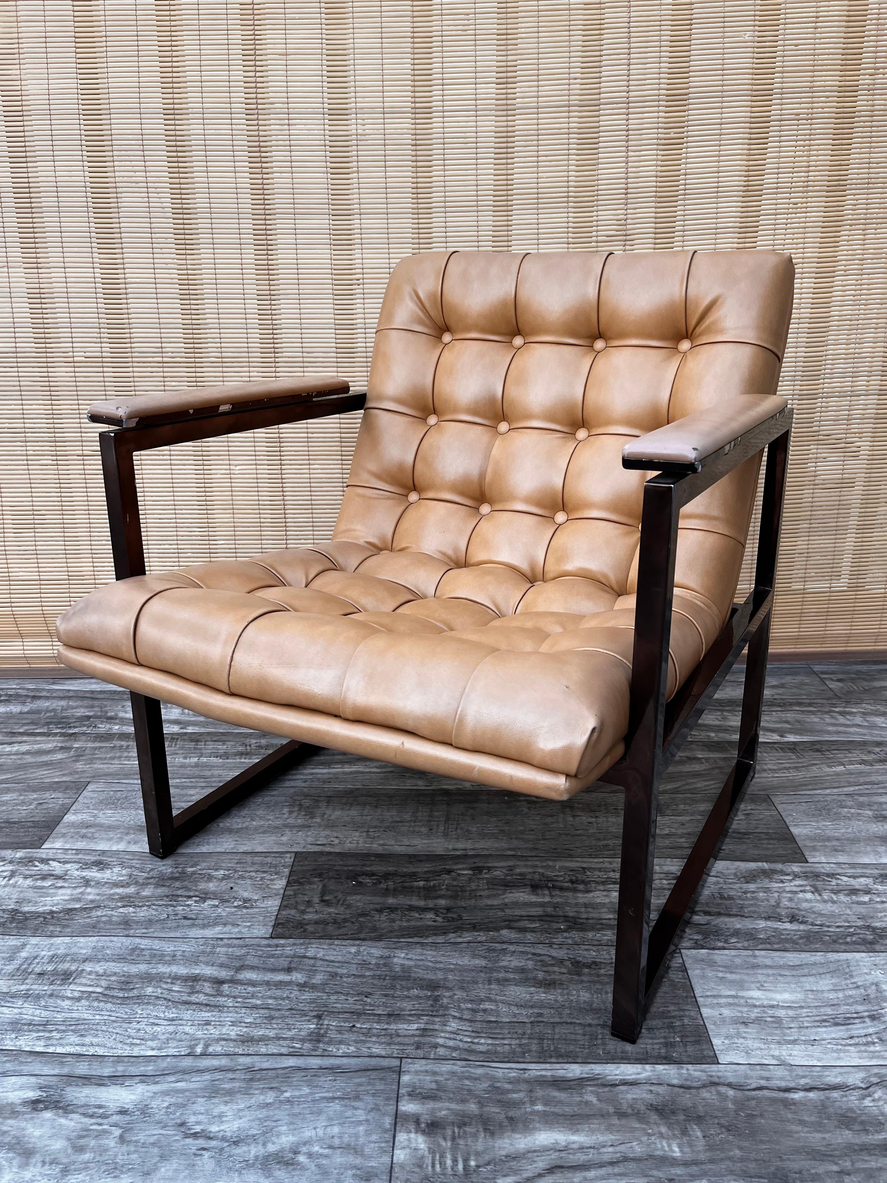 Vintage Mid-Century Modern chrome lounge chair. circa 1970s.
Inspired by Milo Baughman and the Barcelona chair by Mies Van der Rohe's designs.
Features a solid metal frame painted in a bronze color and the original tufted camel color vinyl