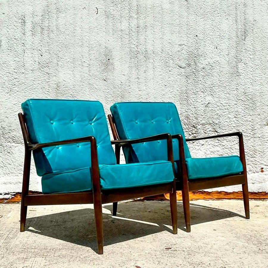 Exceptionnelle paire de chaises de salon de style moderne du milieu du siècle, fabriquées dans le style des designs iconiques de Dux. Dotées de cadres en bois sculpturaux et élégants et de coussins moelleux et confortables, ces chaises allient