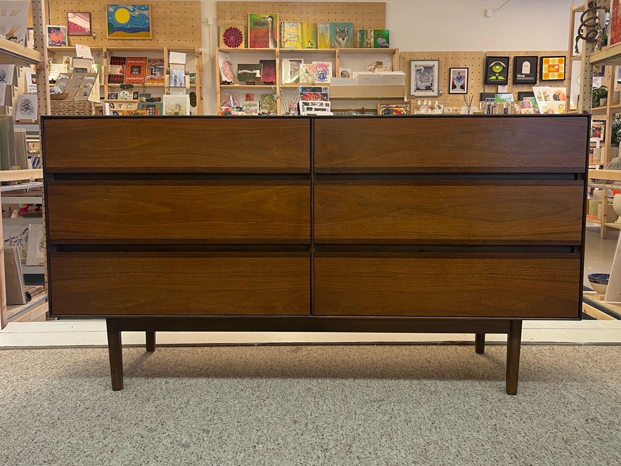 This dresser features 6 Dovetailed Drawers on tapered legs. Walnut toned wood. The Drawer are accented by bands of darker wood grain. Circa 1960s/1970s. Vintage Condition Consistent with Age as Pictured:

Dimensions. 56 W ; 18 D ; 30 H