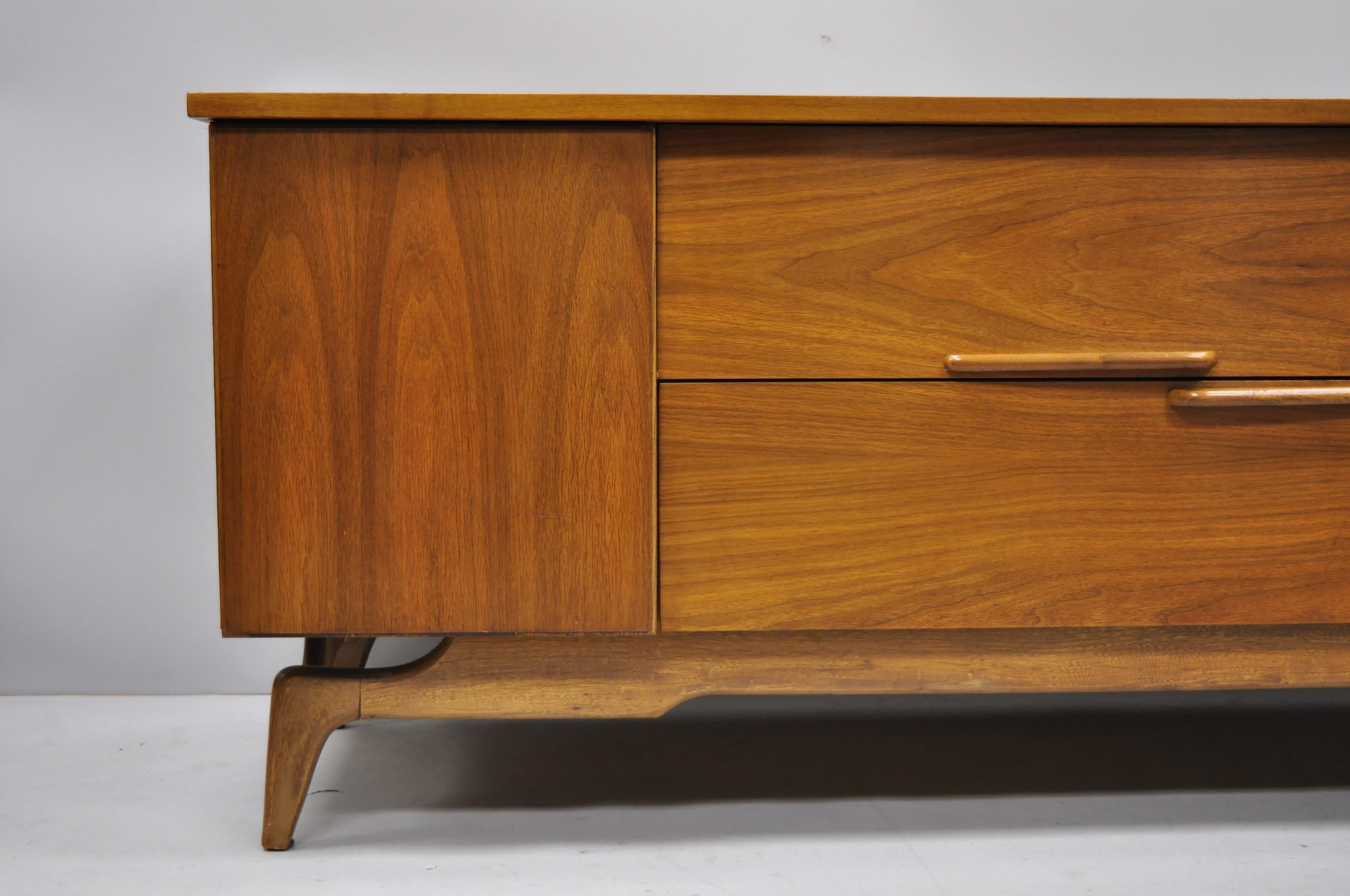 Vintage Mid-Century Modern low sleek walnut credenza cabinet TV console. Item features beautiful wood grain, 2 swing doors, 4 dovetailed drawers, 1 wooden shelf, sleek sculptural, circa 1960s. Measurements: 25