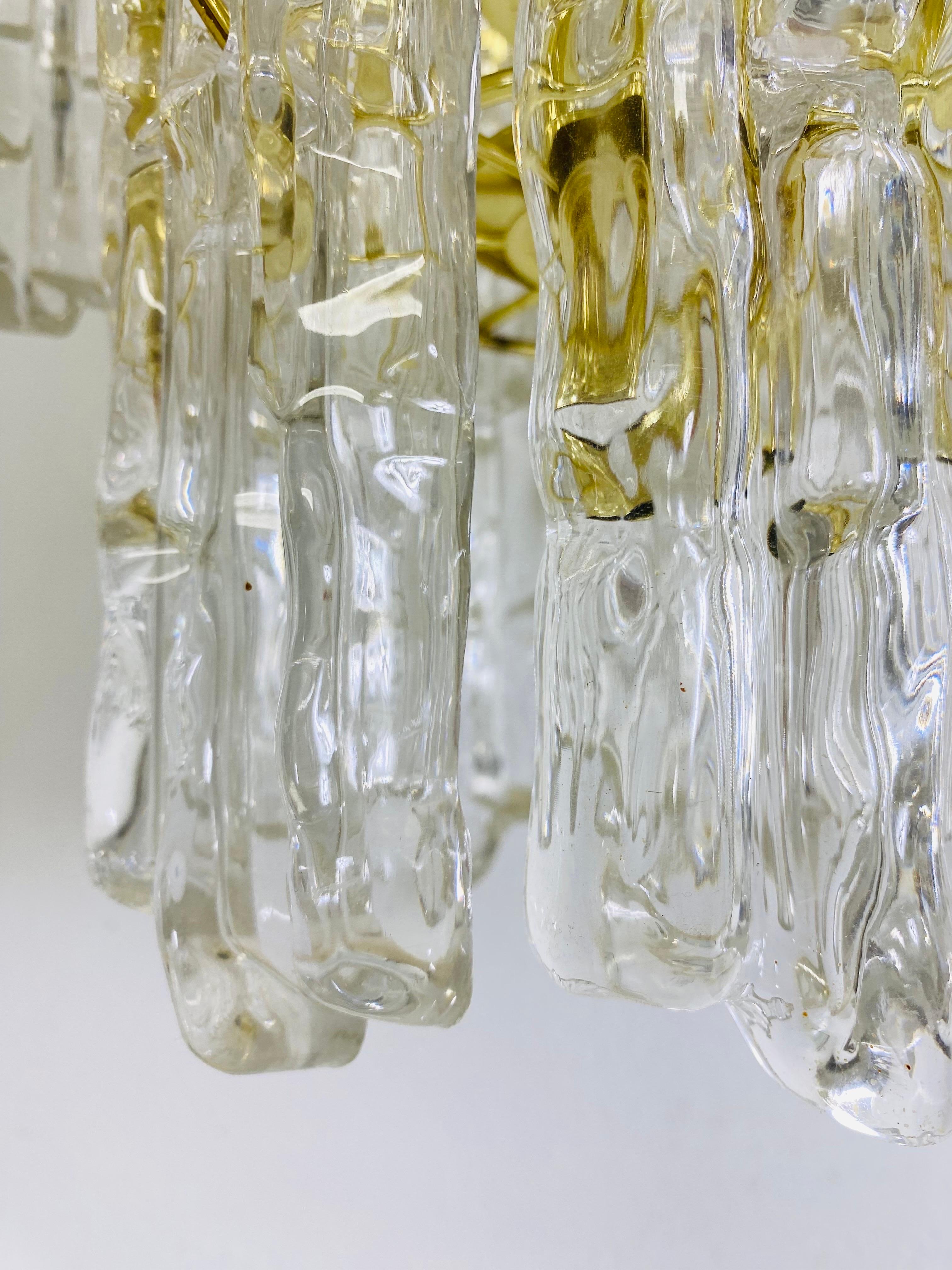 Il s'agit d'un lustre de style cascade en lucite et en laiton datant du milieu du siècle dernier. Ce luminaire comporte de grands panneaux en lucite moulée qui s'insèrent dans le cadre en laiton. Ce qui lui donne un effet de cascade. Ce luminaire