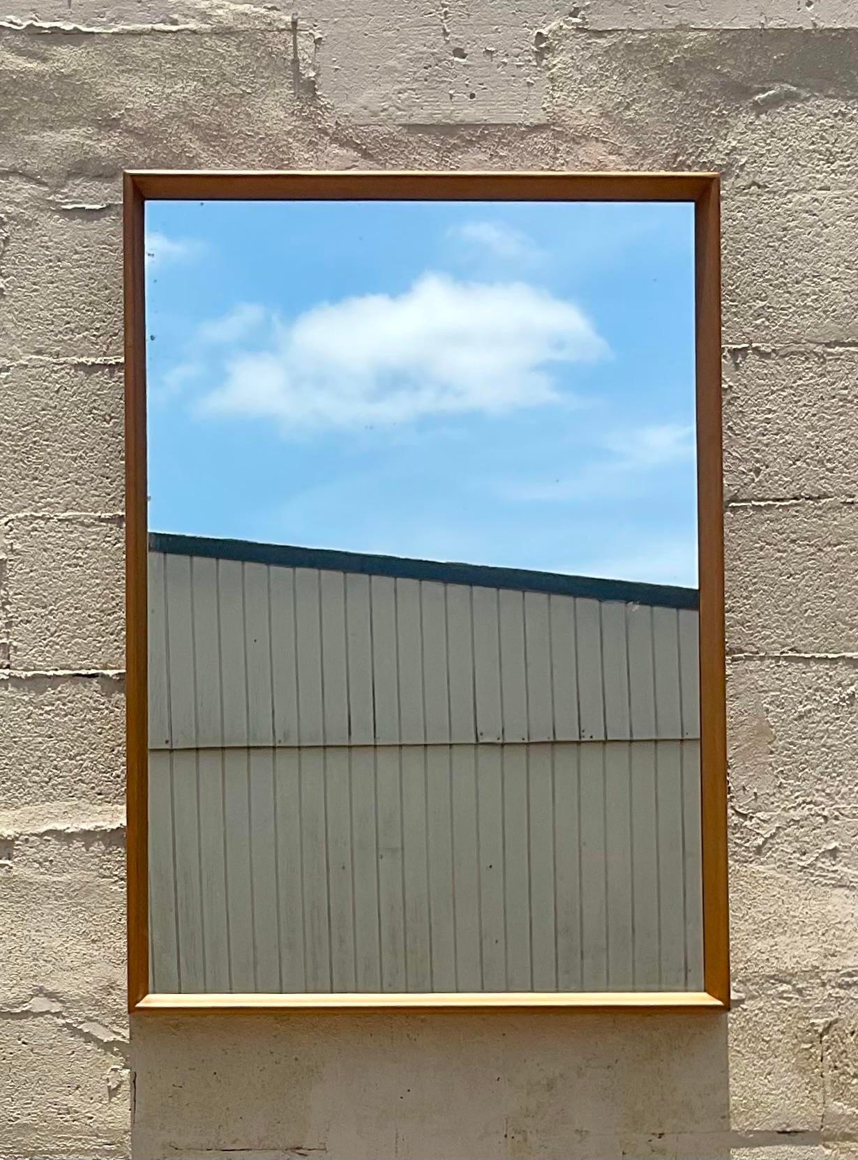 A fabulous vintage MCM wall mirror. A chic and simple design with a solid maple wood frame. Done in the manner of a Heywood Wakefield. Acquired from a Palm Beach estate.