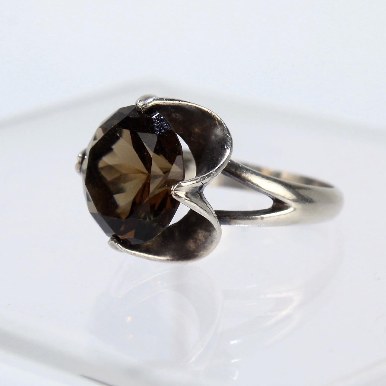 A cool mid-century Mexican sterling silver cocktail ring.

Set with a large round cut smoky quartz gemstone.

Simply a fun, eye-catching ring to wear!

Ring size: ca. 6 1/2
Width: ca. 3/4 in.
Height: ca. 1 in.

Items purchased from this dealer must