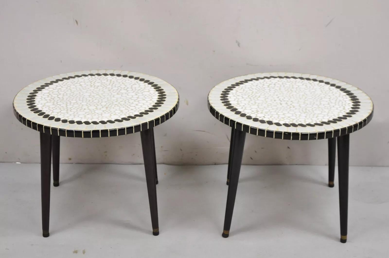 Vintage Mid Century Modern Mosaic Tile Top Round Low Side Tables - ein Paar. Der Artikel verfügt über graue, schwarze und weiße Keramikfliesen, spitz zulaufende Holzbeine (eines mit schwarzen Beinen, das andere mit braunen Beinen), klare