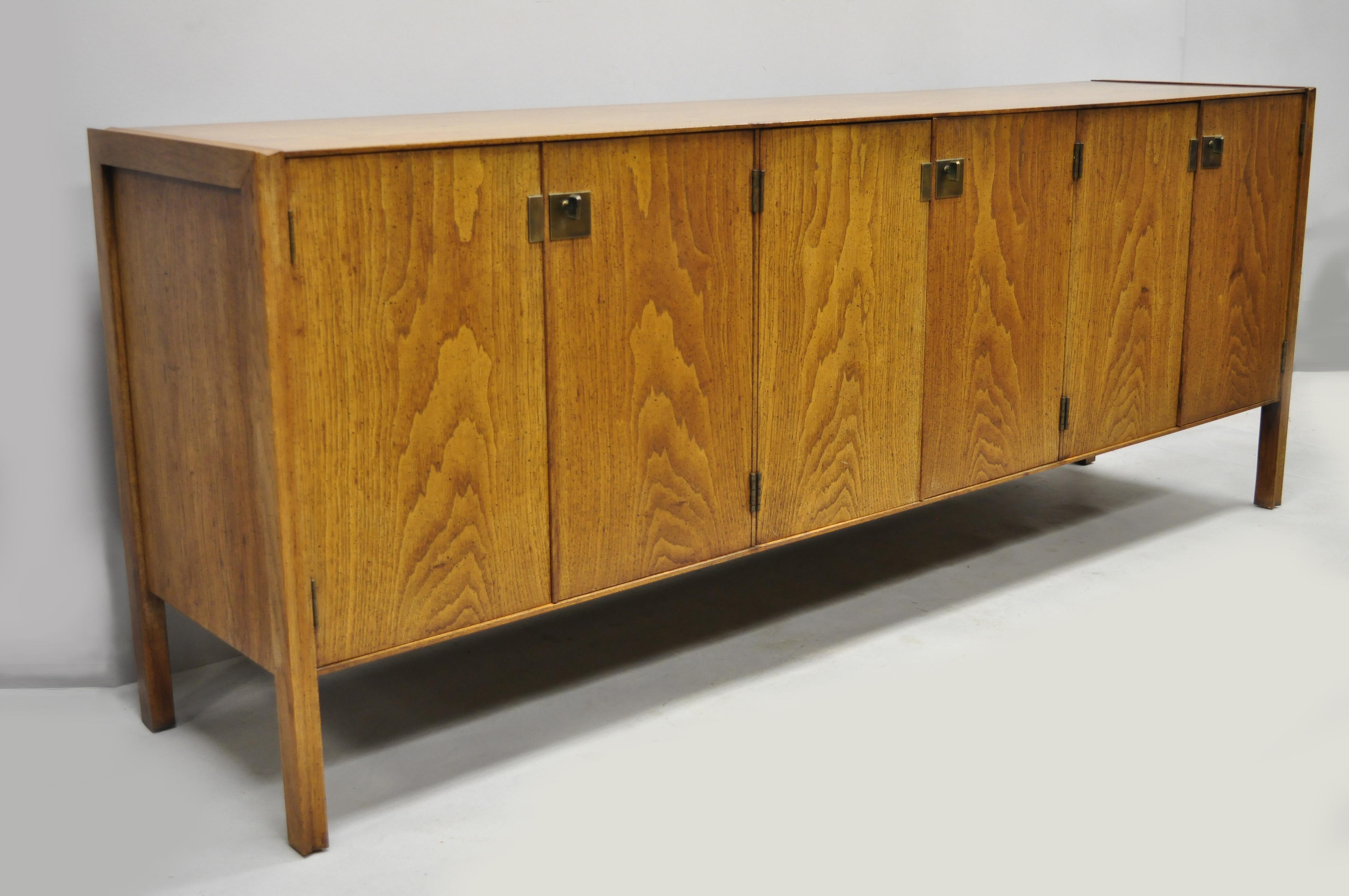 Vintage Mid-Century Modern oak credenza cabinet long buffet after James Mont. Item features beautiful wood grain, distressed finish, 6 swing doors, 3 dovetailed drawers, 3 adjustable shelves, solid brass hardware, clean modernist lines, quality