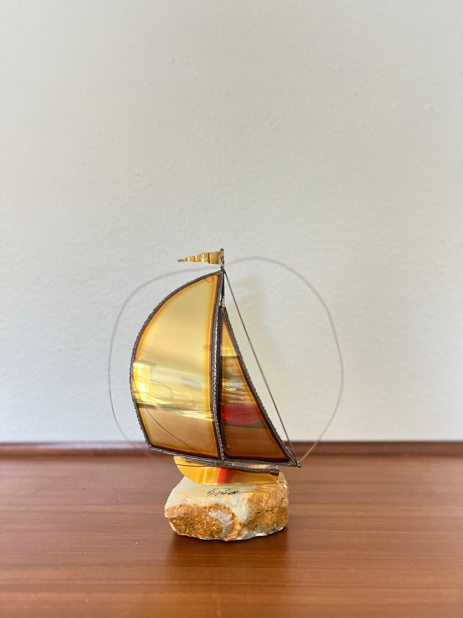 Beautiful brutalist sailboat sculpture of patinated brass sheets and copper wire on a white quartz base. Great movement is evoked in the sails at the pennant at the top mast.

Signed at the base 

The perfect addition to your home decor.