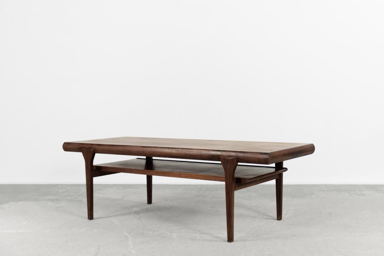 This extendable coffee table was made in Denmark during the 1960s. It is made of strong teak wood in a dark shade of brown. The functional table has a shelf and a pull-out drawer with compartments for small items. The other side of the top slides