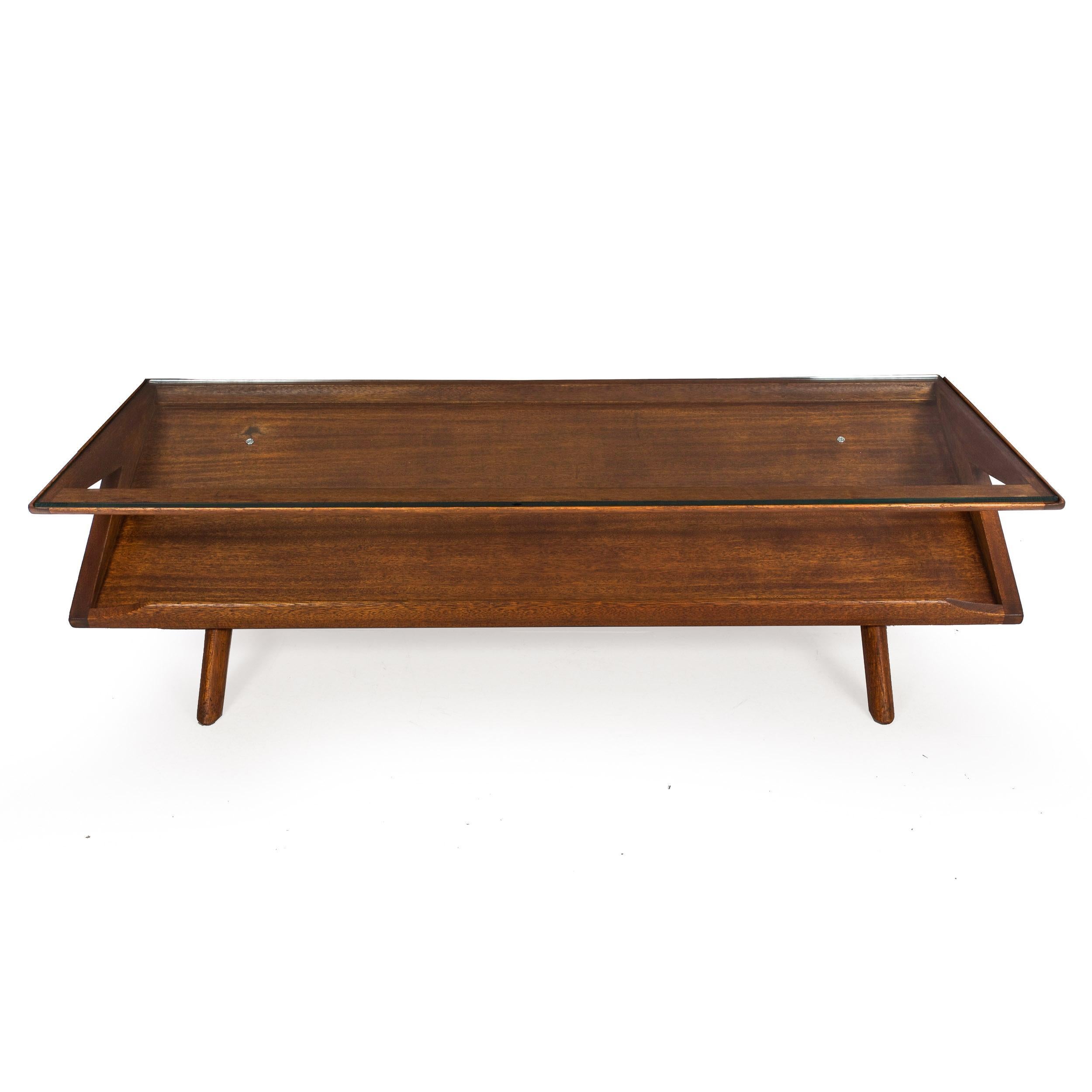 An interesting vintage cocktail table circa the 1960s designed by Paul Laszlo, it features a sharp geometry of severe angles in the molded hardwood frame, the lower angle with a generous lip allowing for the presentation of magazines and books while