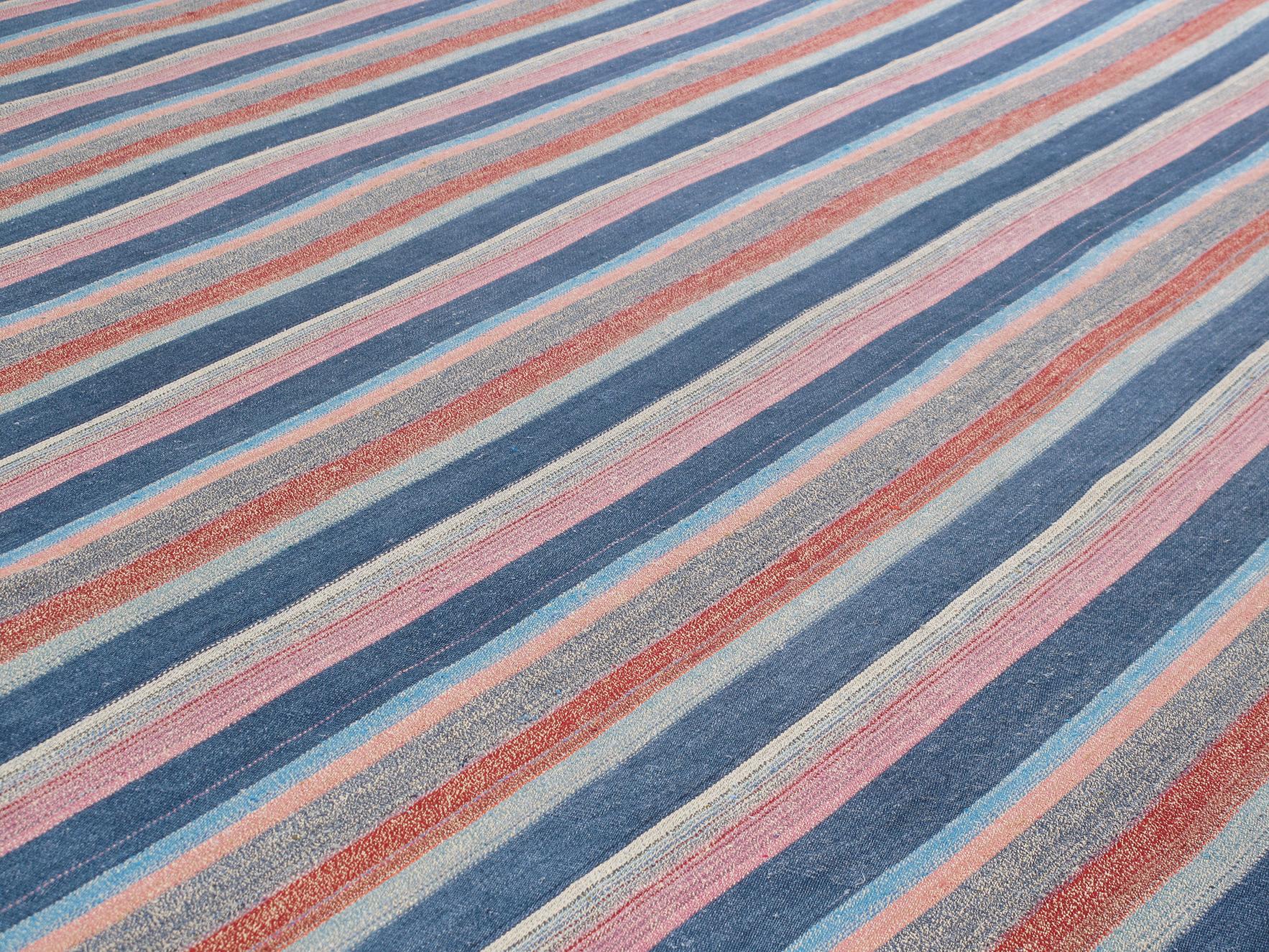 Ce tapis tissé à plat et à rayures multiples est fabriqué avec la meilleure laine persane cardée et filée à la main, et les couleurs riches et vibrantes proviennent de teintures naturelles issues de plantes et de minéraux régionaux. Tailles et