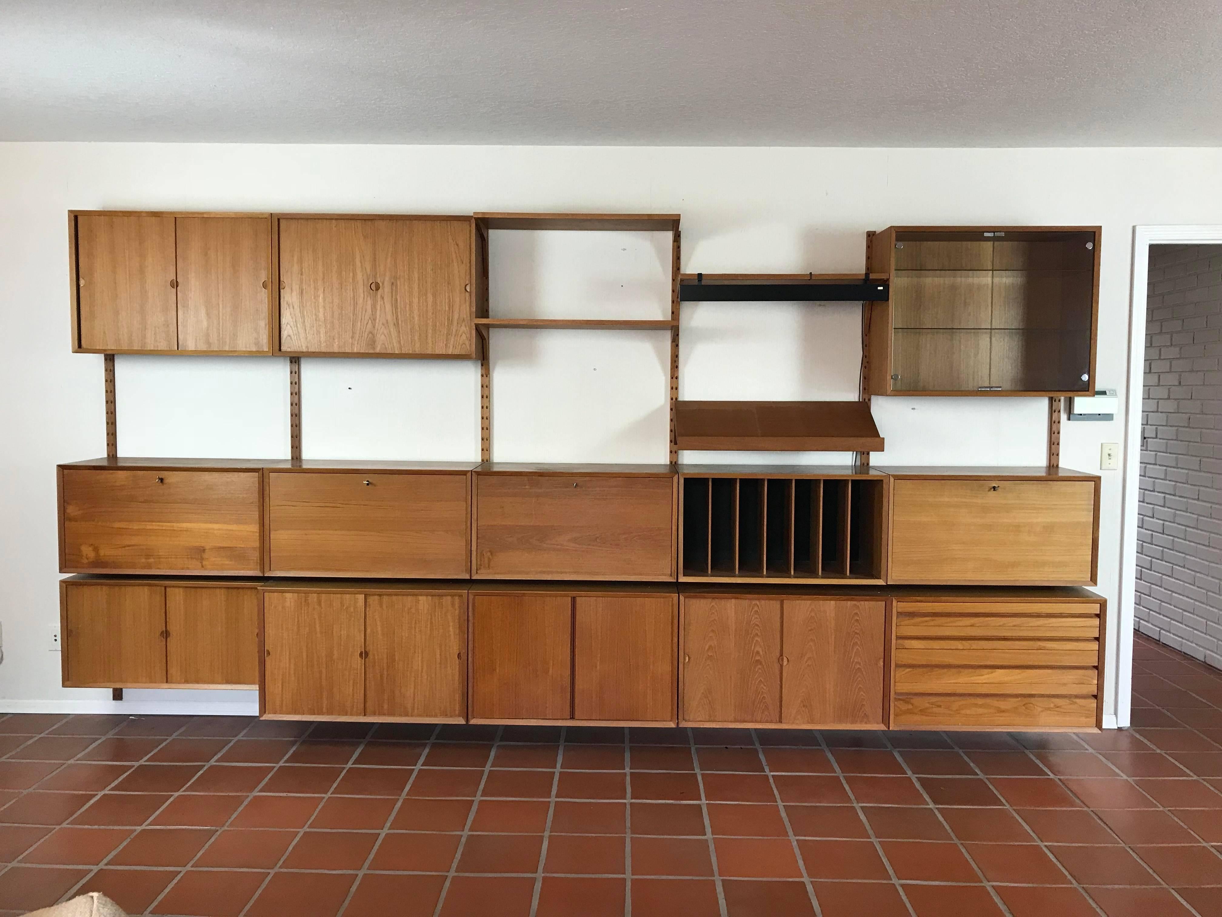 Fantastic vintage Mid-Century Modern Poul Cadovius designed Cado wall unit in teak. As shown it measures 158 inches wide, 83 inches tall and maximum depth of 19 inches. 

Included are:
Four drop front cabinets with keys,
Five cabinets with