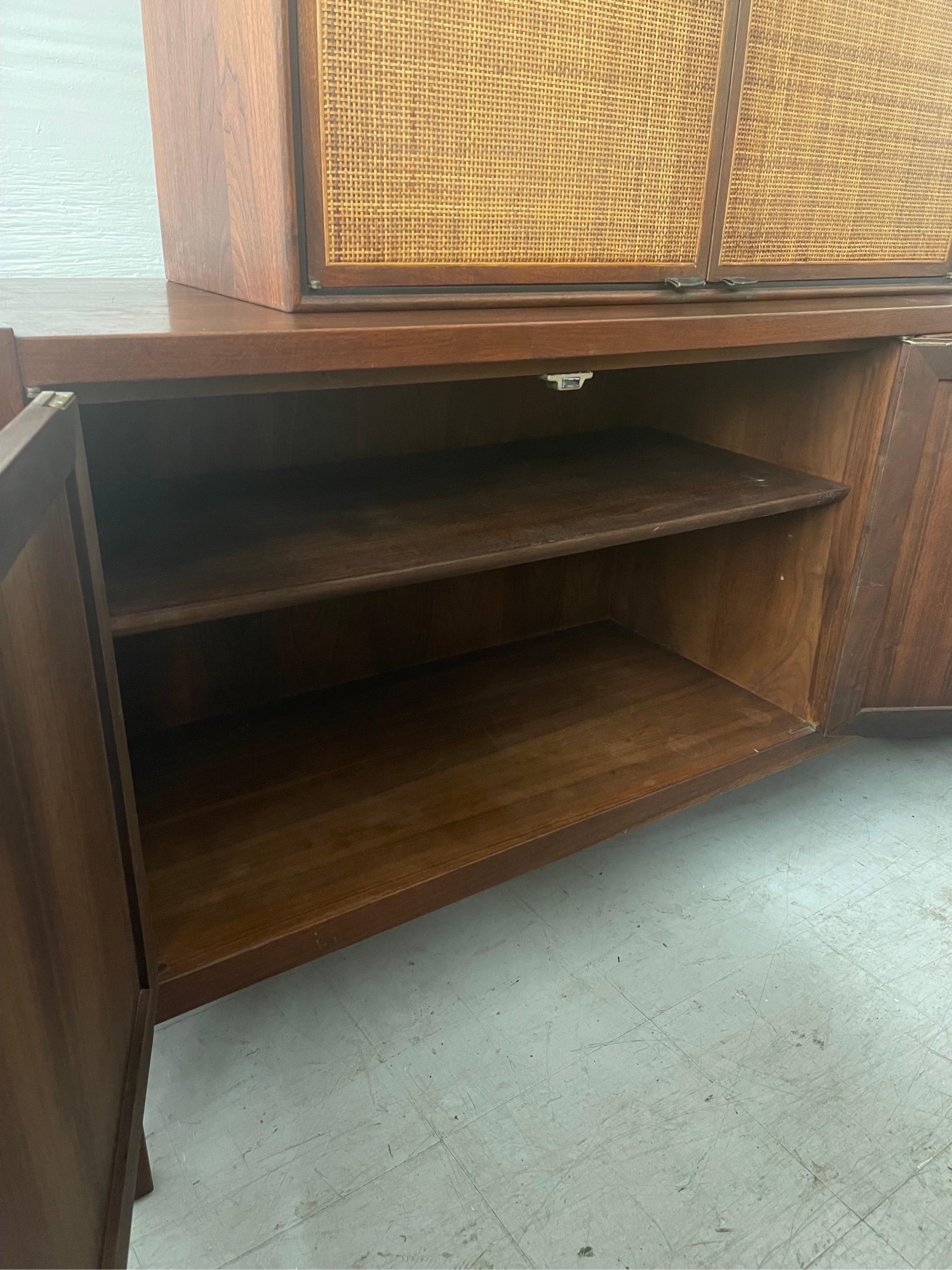 Vintage 2-piece mid century credenza with caned accents. The top portion serves as a storage cabinet with height adjustable shelves. The credenza includes spacious drawers and height adjustable shelving on the left side.

The top is removable, if