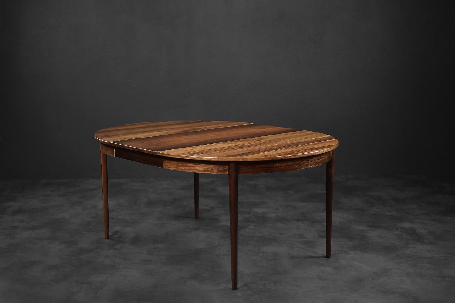 This modernist dining table was made in Denmark during the 1960s. It is made of precious rosewood in a warm shade of brown. It is characterized by attractive graining and high-quality workmanship. The table is endowed with three extra tops that can