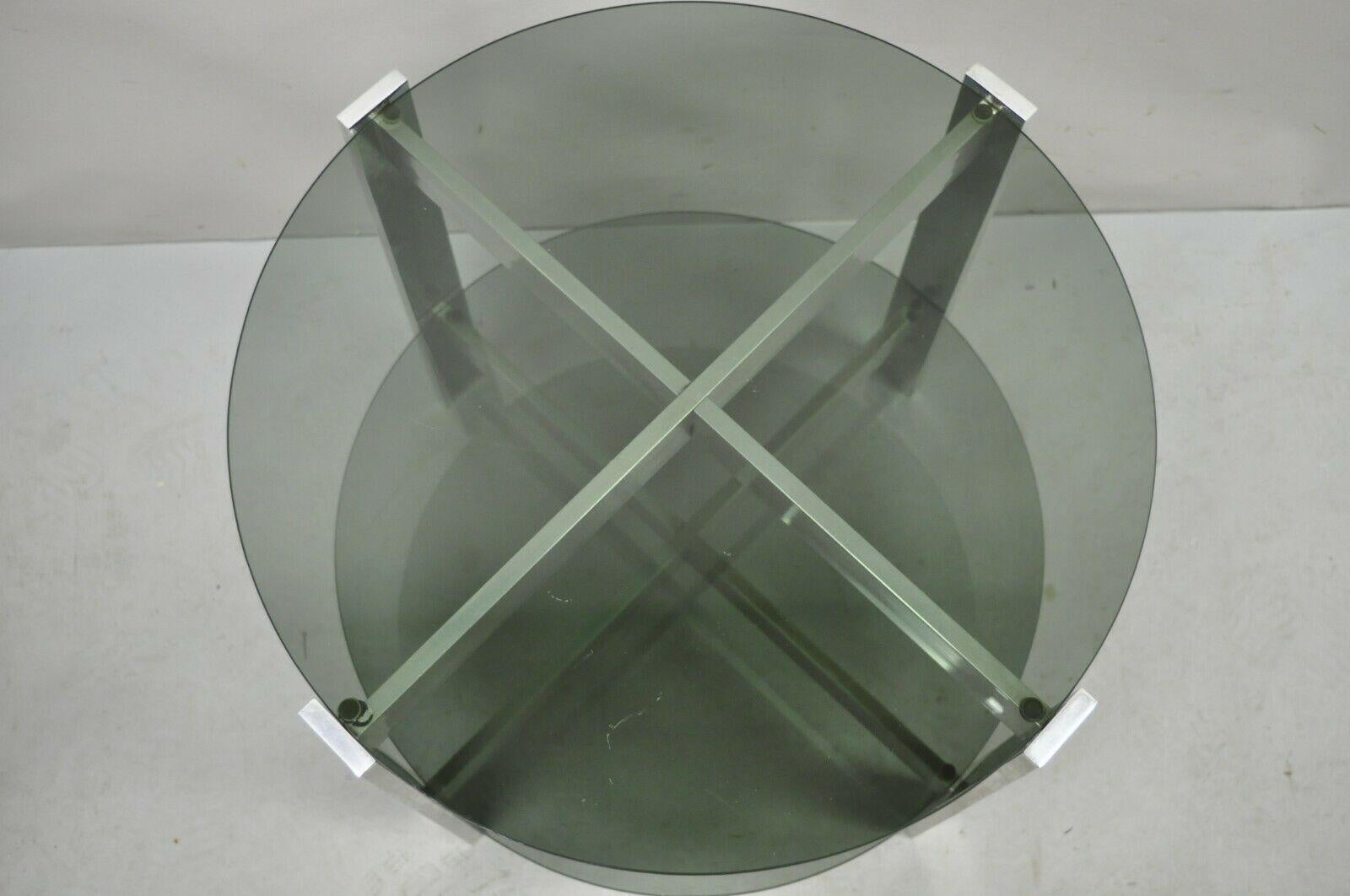 Table d'appoint ronde en verre fumé à 2 niveaux avec base en aluminium, de style moderne du milieu du siècle dernier. L'article comprend (2) plateaux ronds en verre fumé, un cadre en aluminium moulé en forme de X, un style et une forme modernistes
