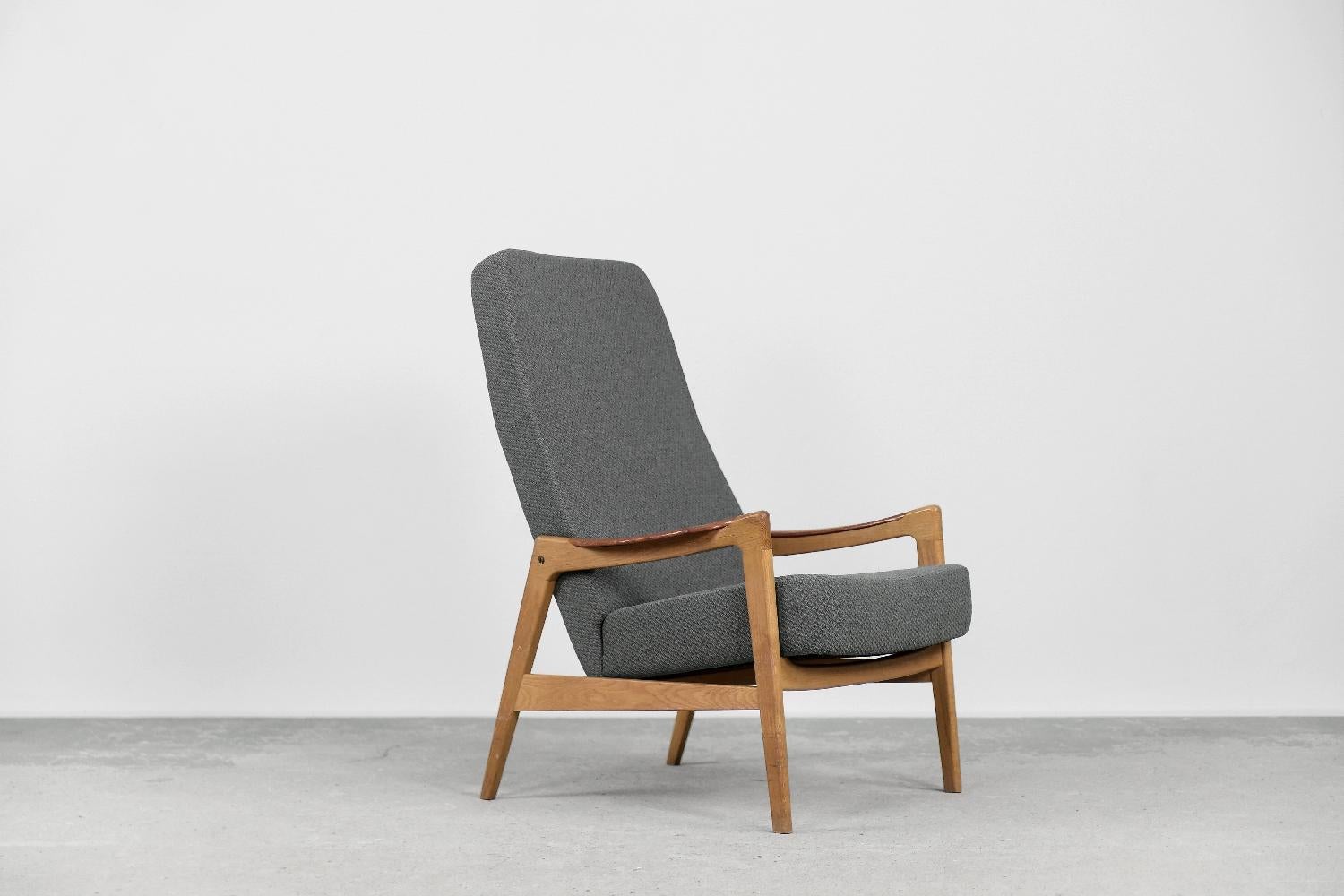 This modernist armchair was made by the Swedish manufacture OPE Möbler during the 1960s. The frame is made of solid oak wood in a light shade of brown. The armrests are made of teak. The seat and high backrest have been reupholstered with a