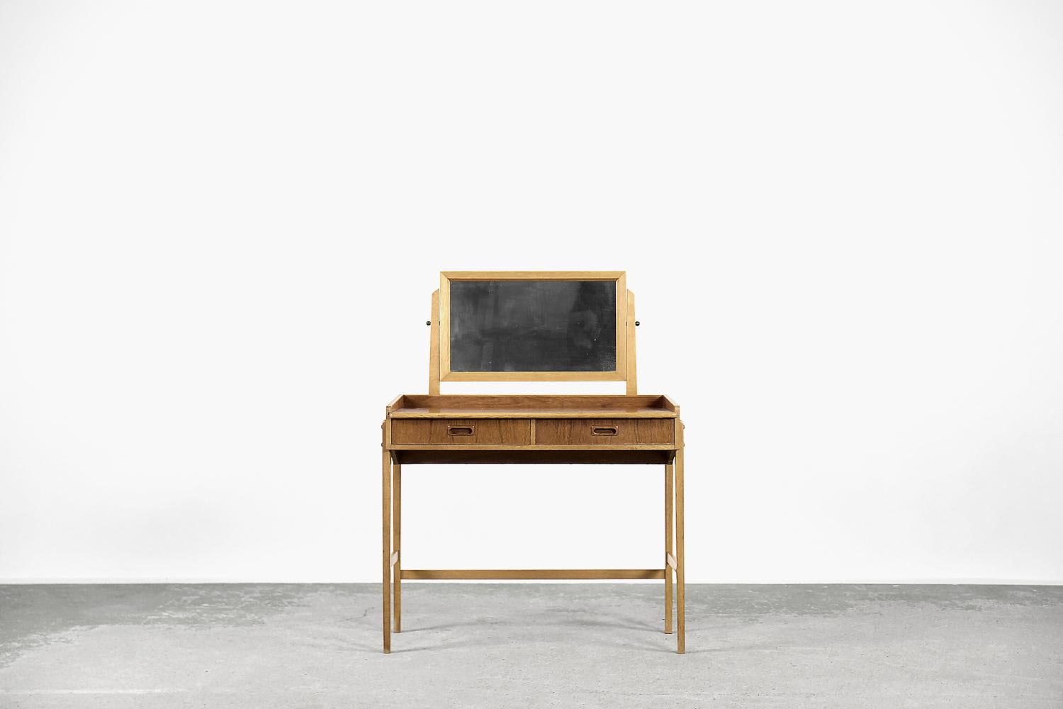 This modernist dressing table with a mirror was made in Sweden during the 1960s. It is made of teak wood in a warm shade of brown. It has two spacious drawers and a pull-out top with a partition. The mirror can be adjusted at any angle.

This