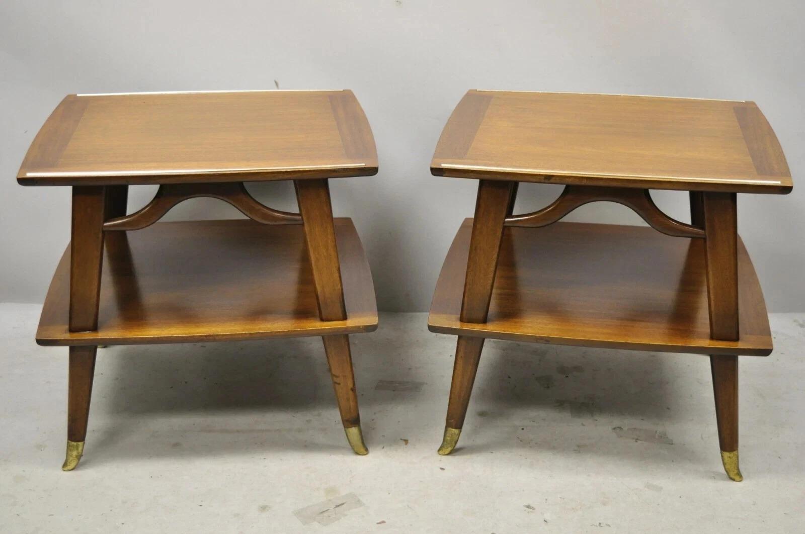 Vintage Mid Century Modern Sculpted Walnut 2 Tier End Tables w/ Brass Feet - Pair. Item features metal capped brass plated feet, lower shelf/tier, beautiful wood grain, nicely carved details, tapered legs, sleek sculptural form. Circa Mid 20th